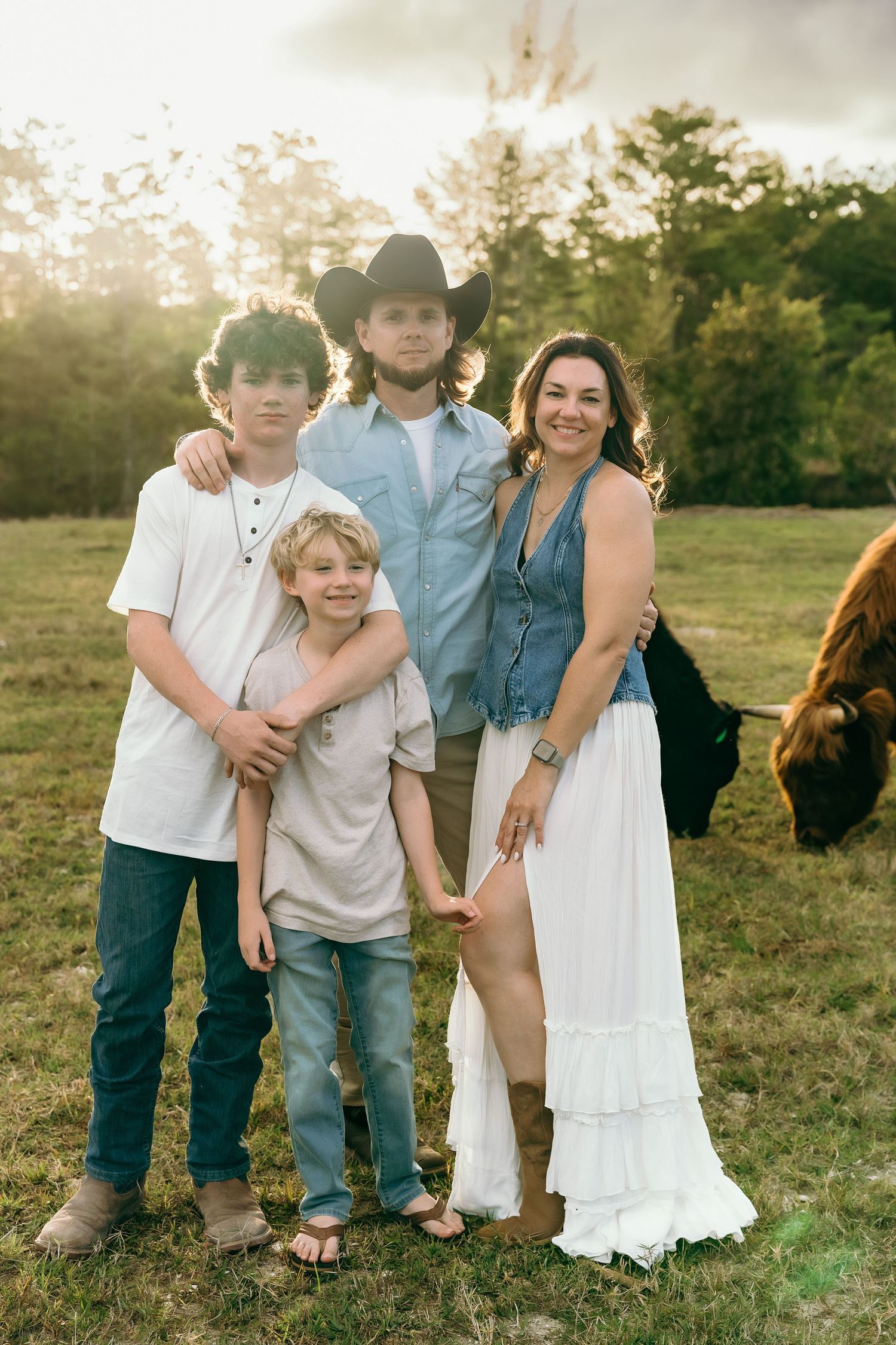 Family enjoying a playful moment together outdoors in a grassy field at sunset.