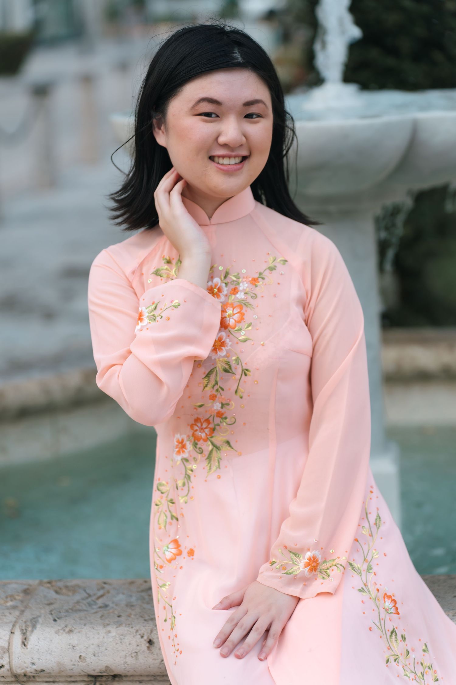 A pink floral embroidered dress photographed in an outdoor garden setting.
