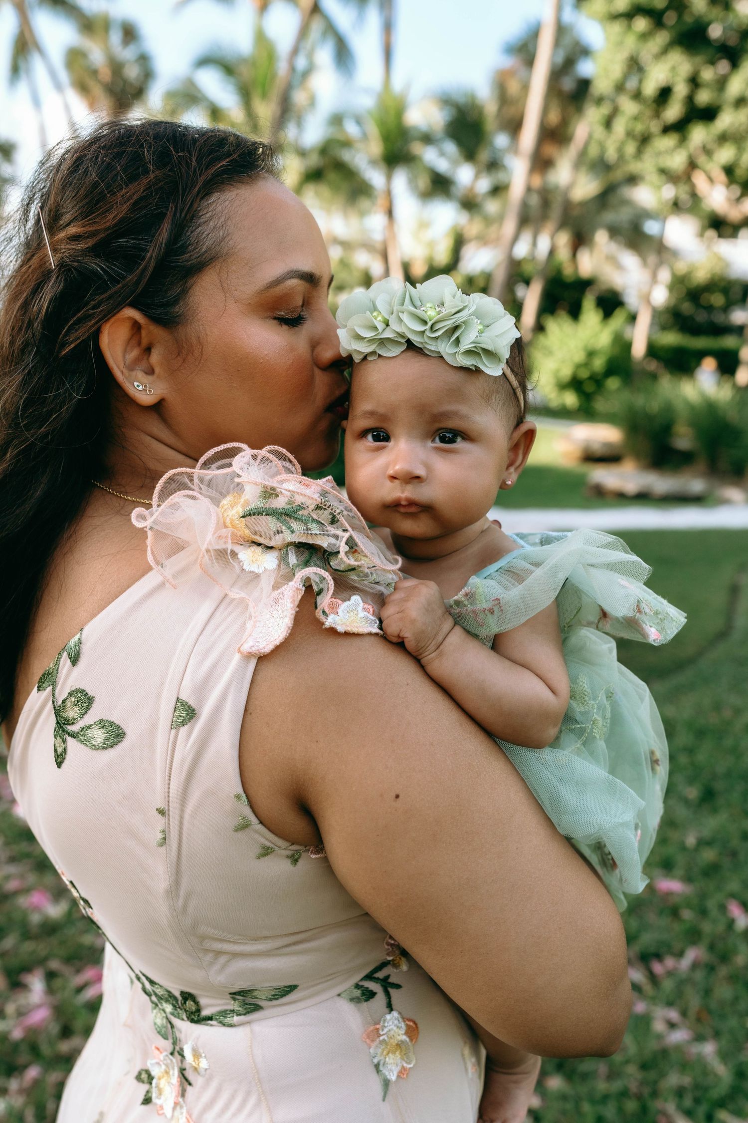 A tender moment captured in a series of photos showing a parent and baby embracing in an outdoor garden setting.