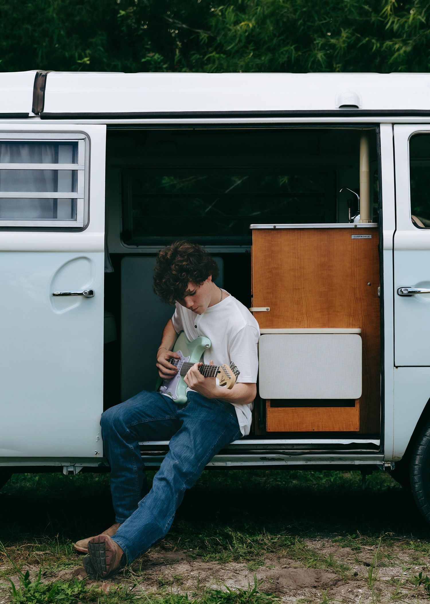 Person lying inside vintage white van while using camera equipment.