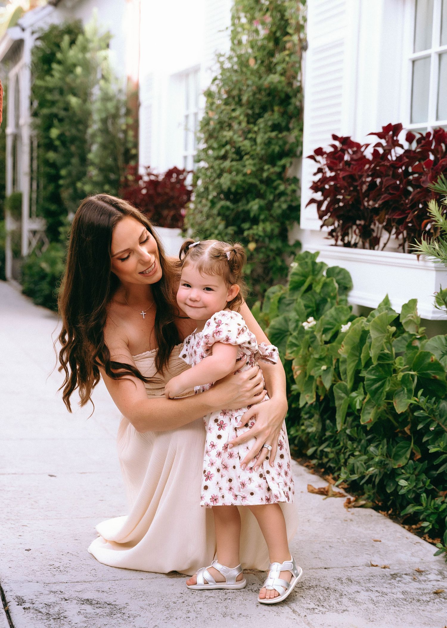 A tender moment shared between two people on a garden path with lush greenery.