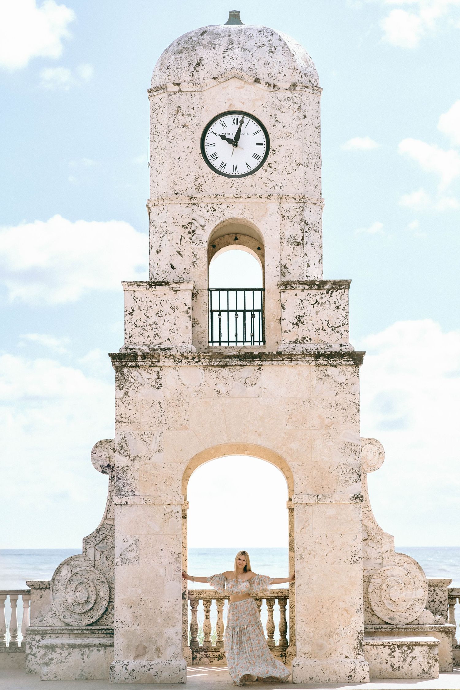 Ancient stone clock tower with arches against a bright blue sky.