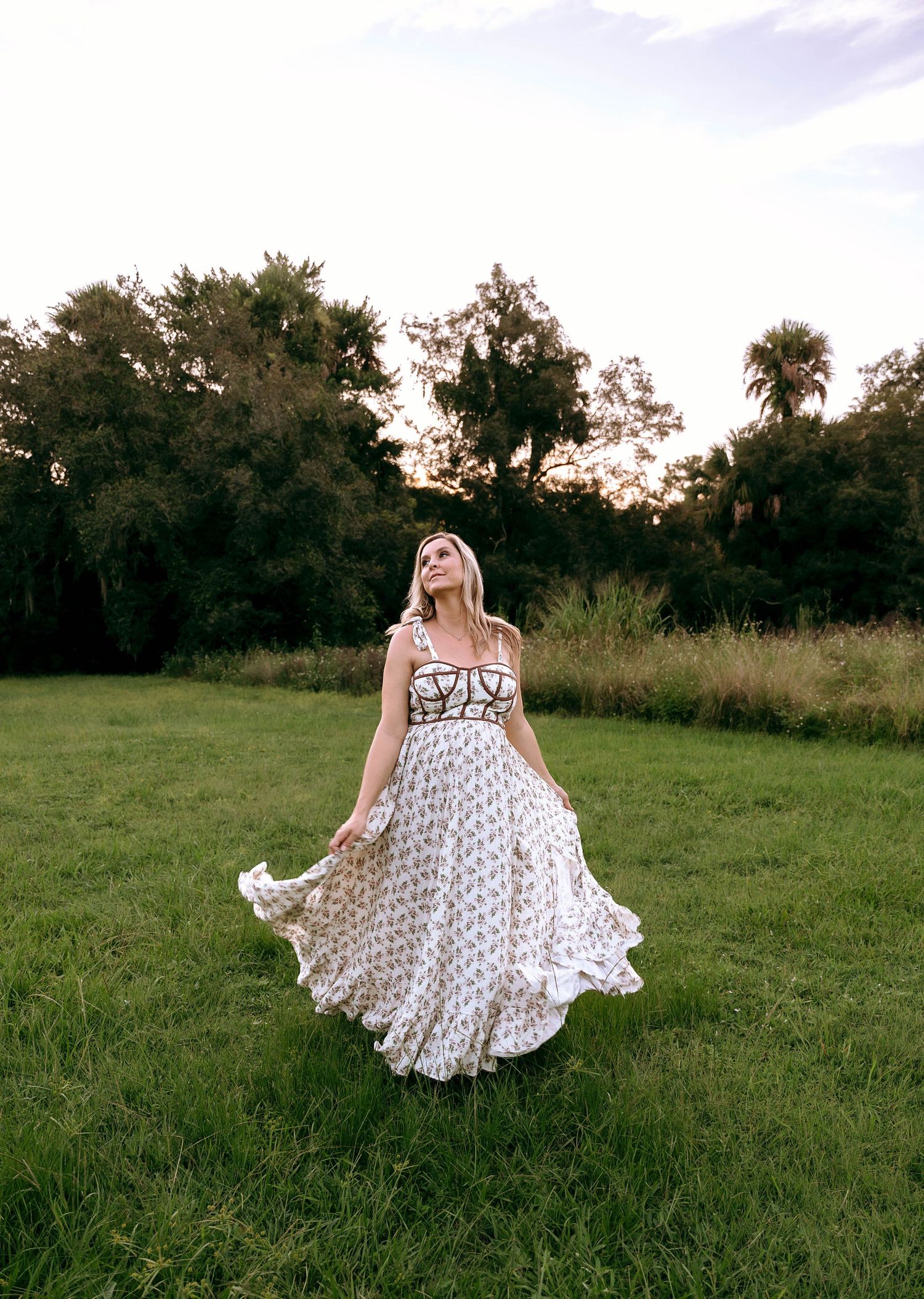 A white sundress with delicate patterns flows in the breeze against a natural outdoor backdrop.