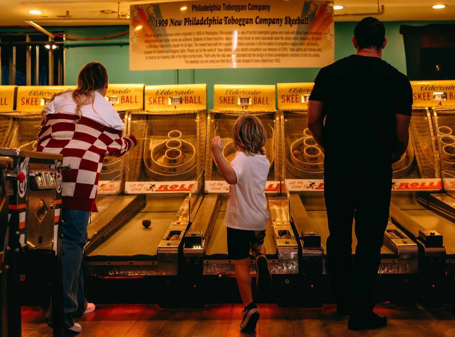 Children and adults playing Skee-Ball at Philadelphia Toboggan Company arcade game attraction.
