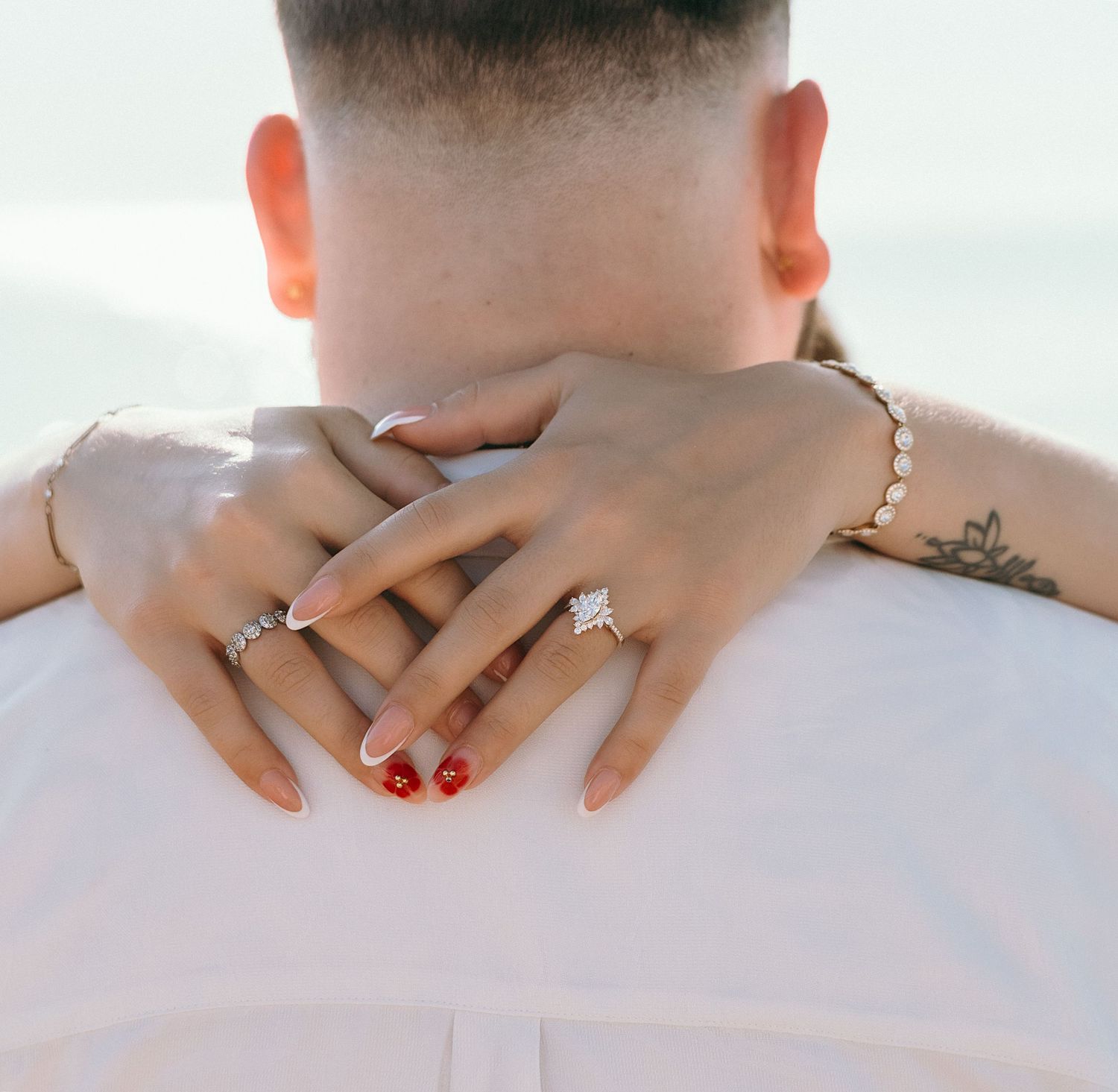 Close-up shot showing hands with red nails against white fabric.