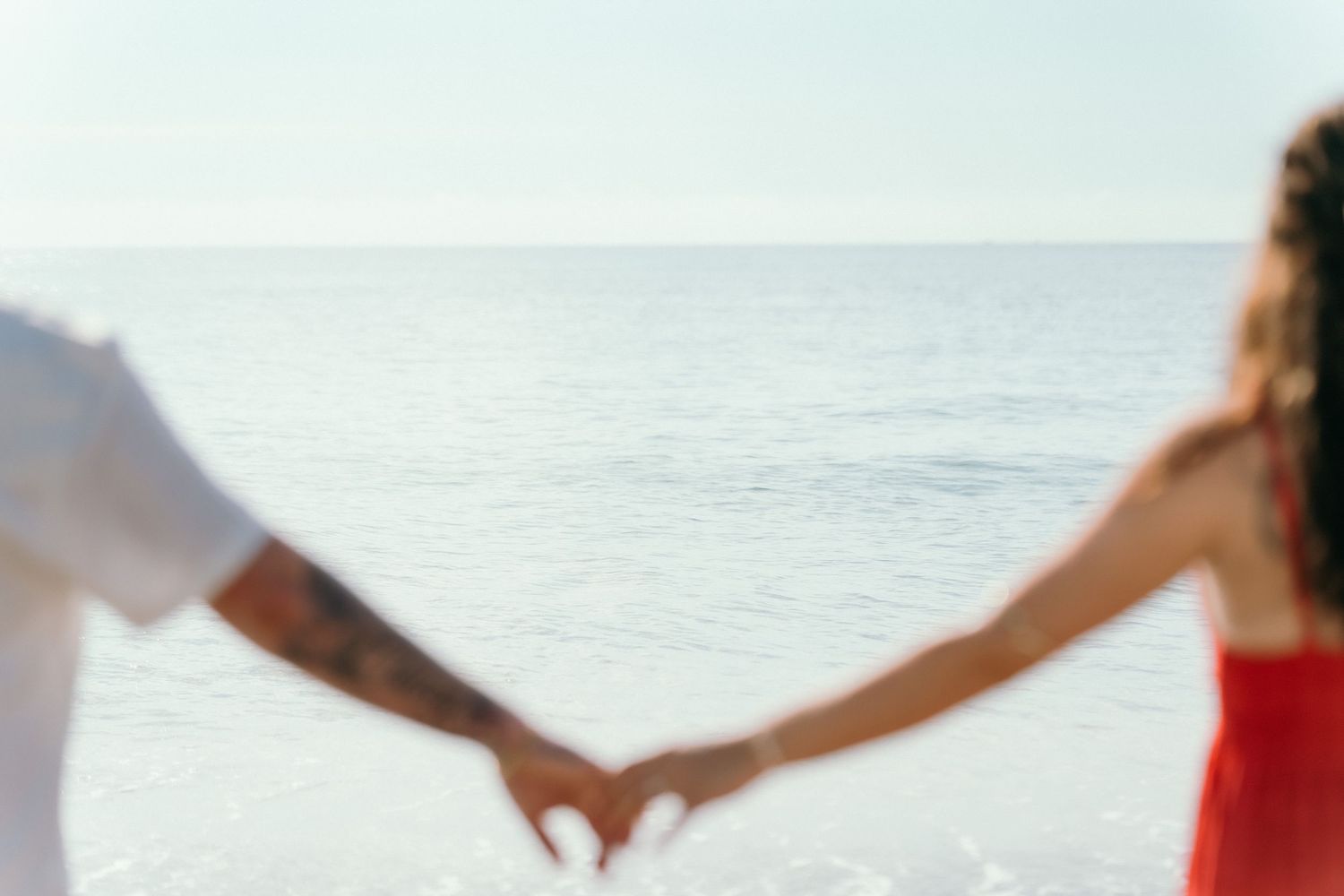 Hands forming heart shape against bright ocean background.