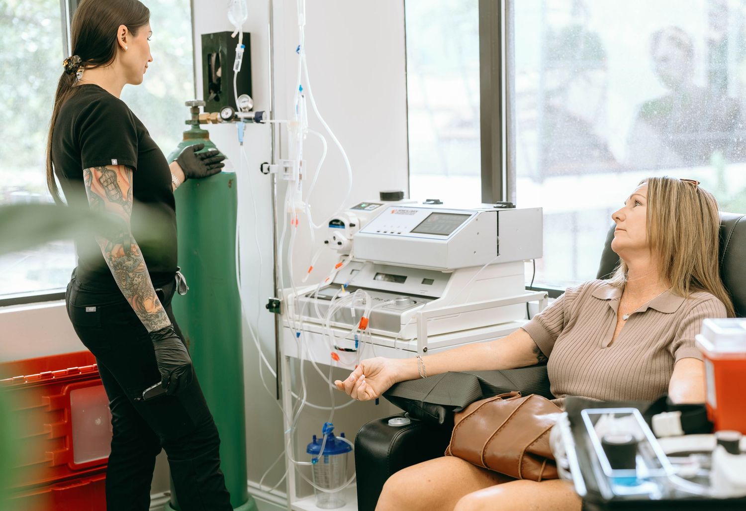 A healthcare worker assists a patient receiving IV therapy treatment in a modern medical clinic.