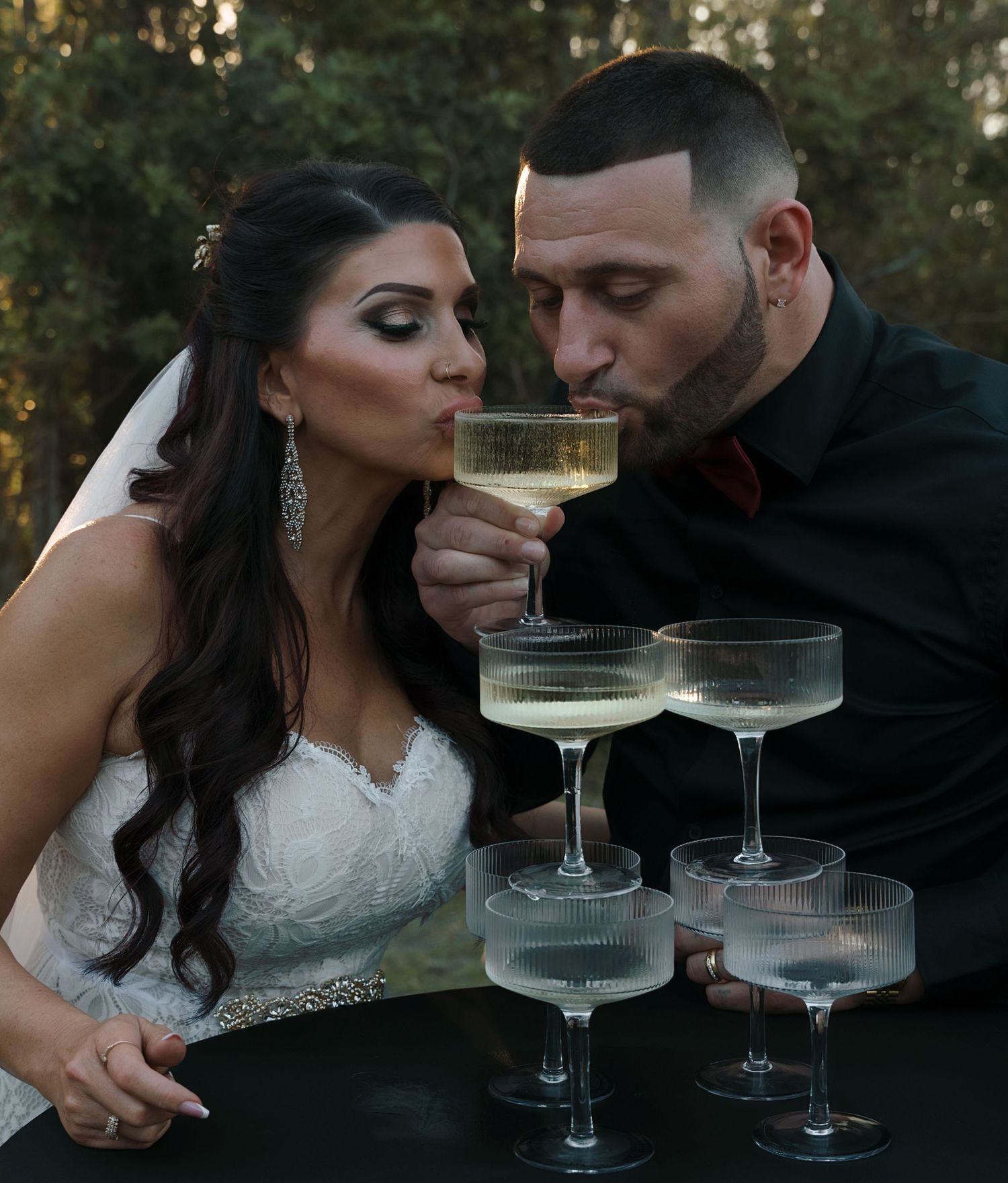 Wedding couple sharing champagne in an intimate moment during sunset.