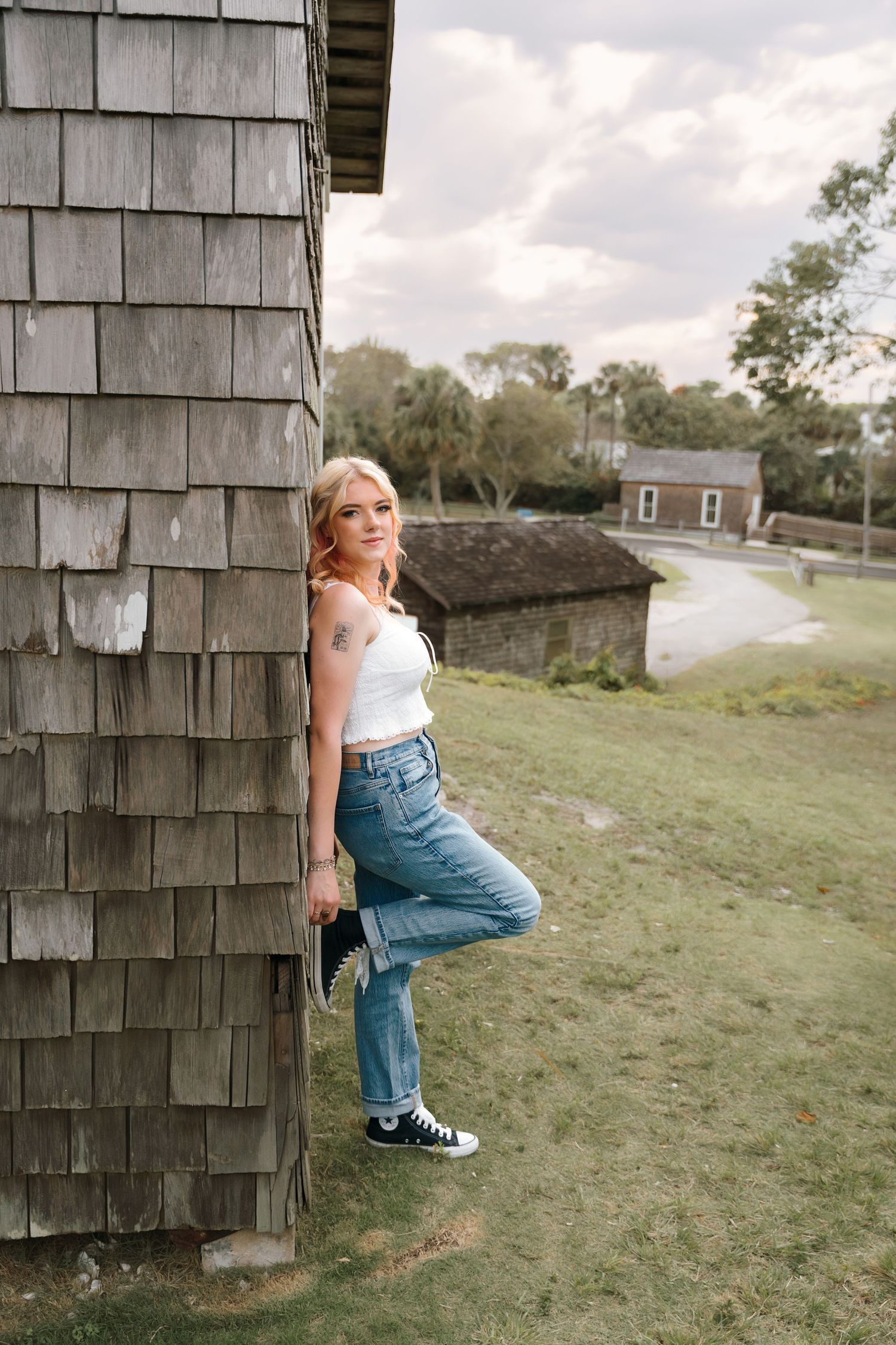Rustic outdoor photoshoot against weathered wood siding in casual attire.