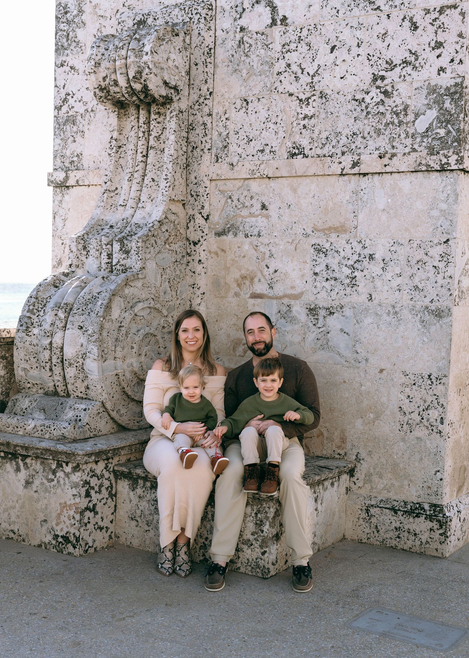 Family portrait session against weathered stone wall.