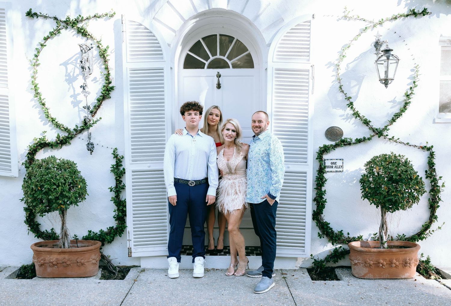 White architectural backdrop with climbing vines and decorative shutters in a photo series.