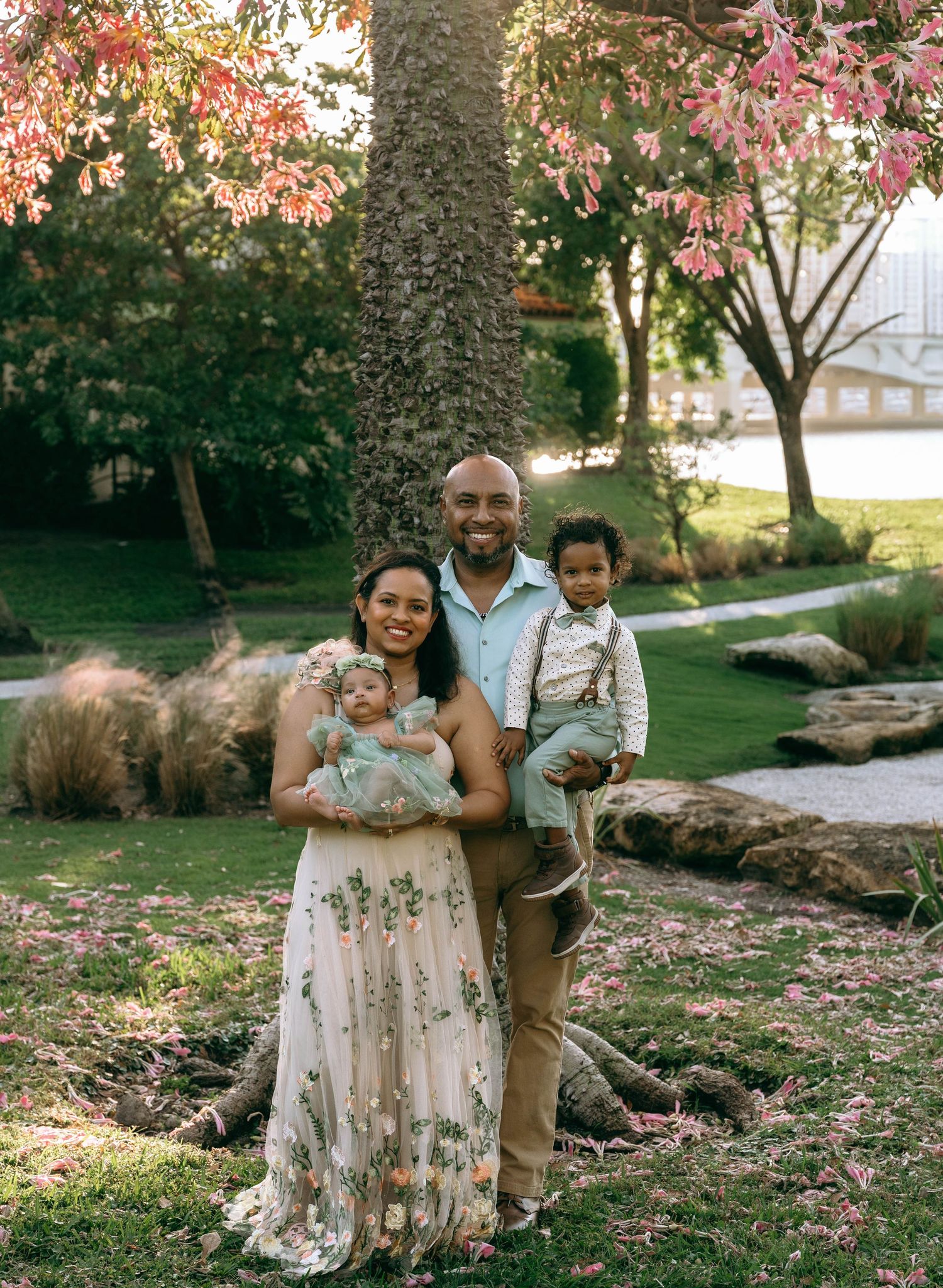 Family portrait session in a park with blooming cherry trees and natural lighting.
