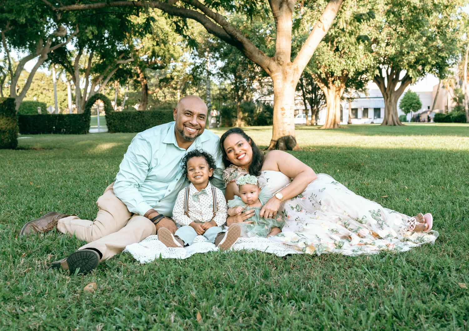 Family enjoying a picnic on grass under trees at sunset.