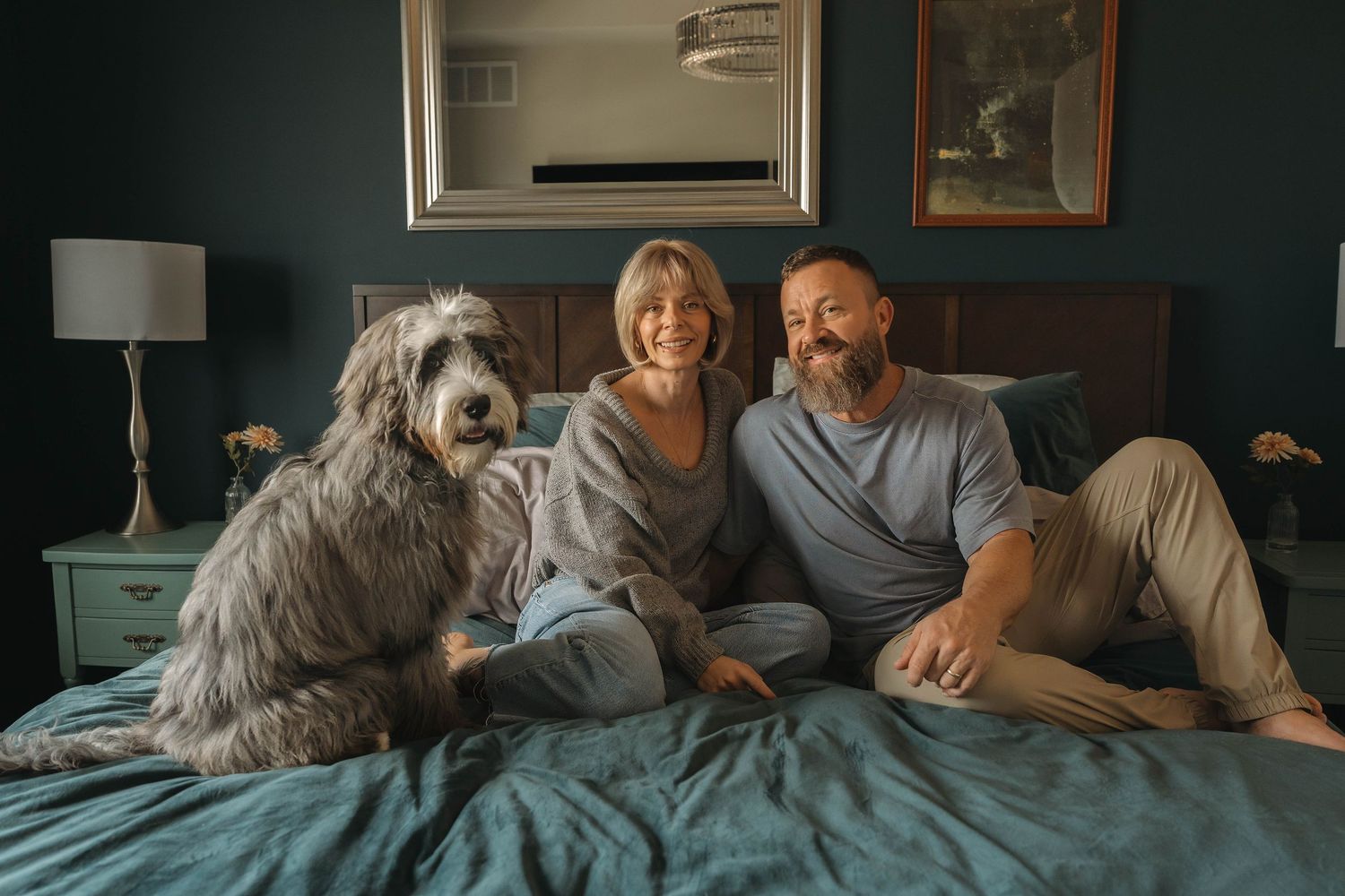 An intimate family moment captured in a dimly lit bedroom with a pet dog.