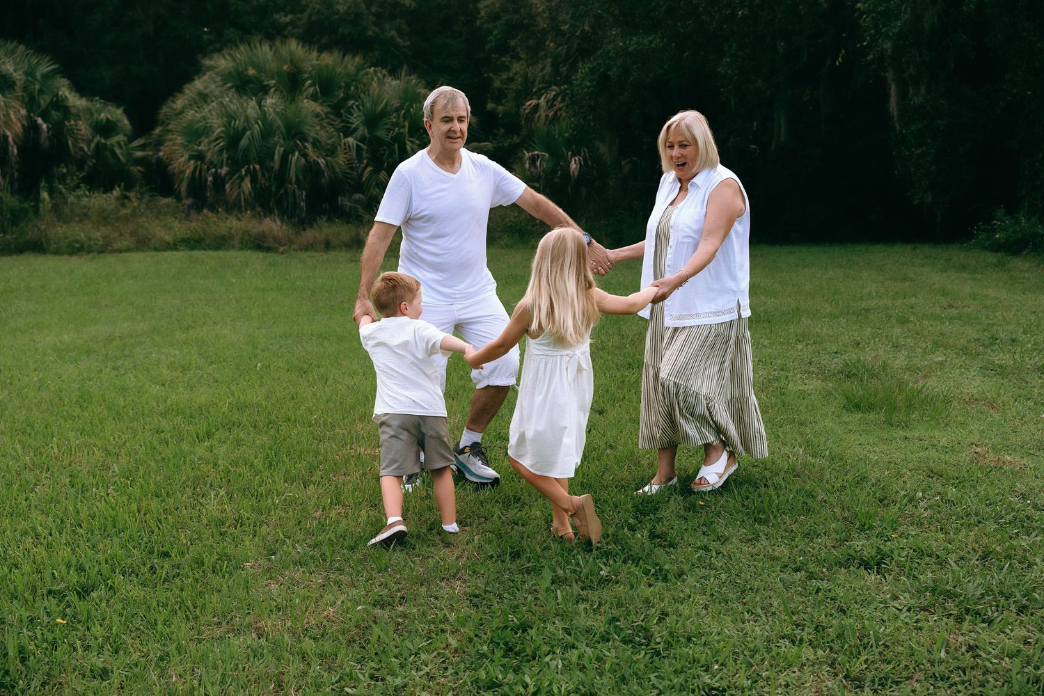 Family members in white outfits enjoying active playtime outdoors.