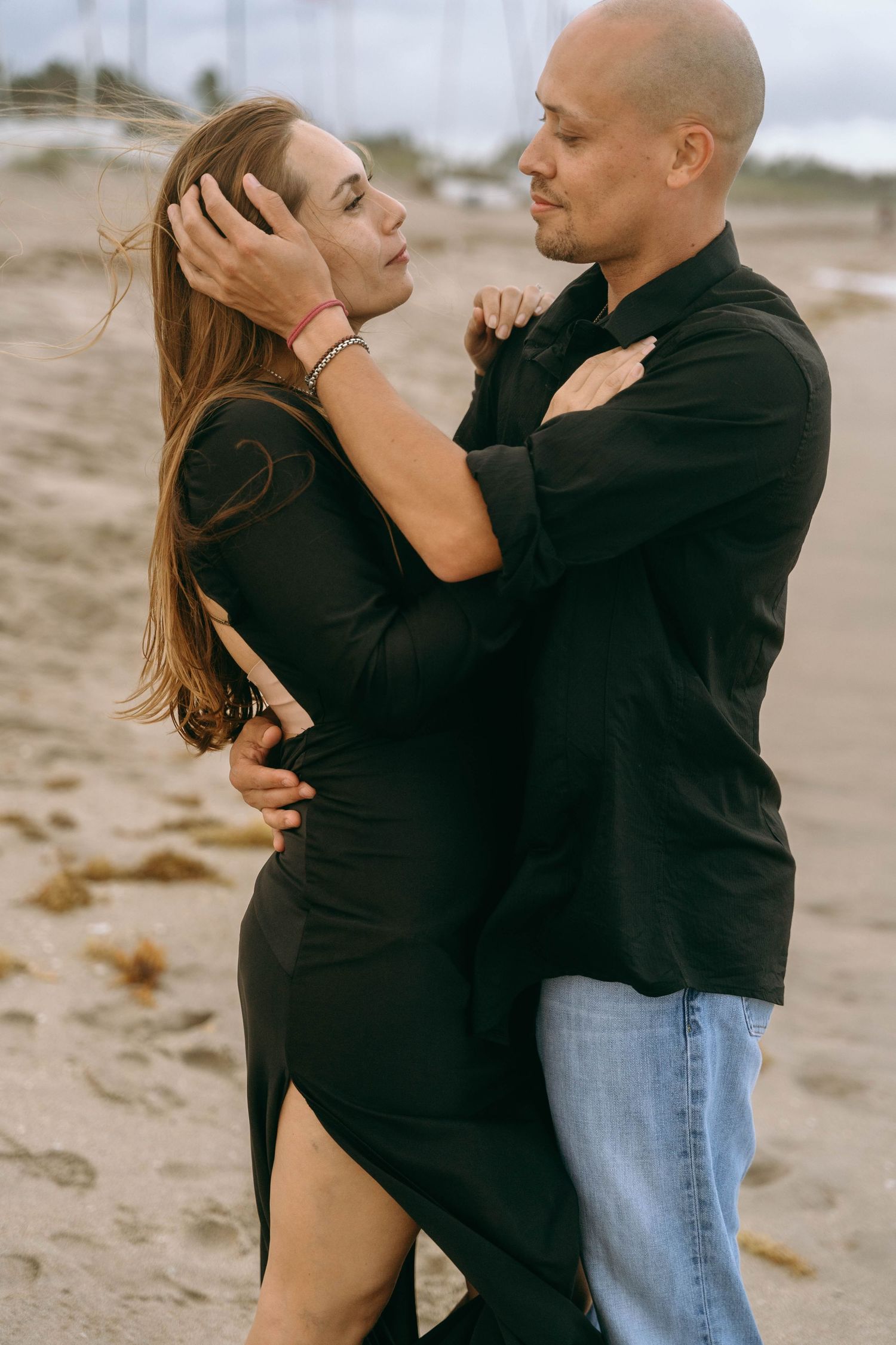 A romantic couple embraces on a sandy beach during an intimate photoshoot.