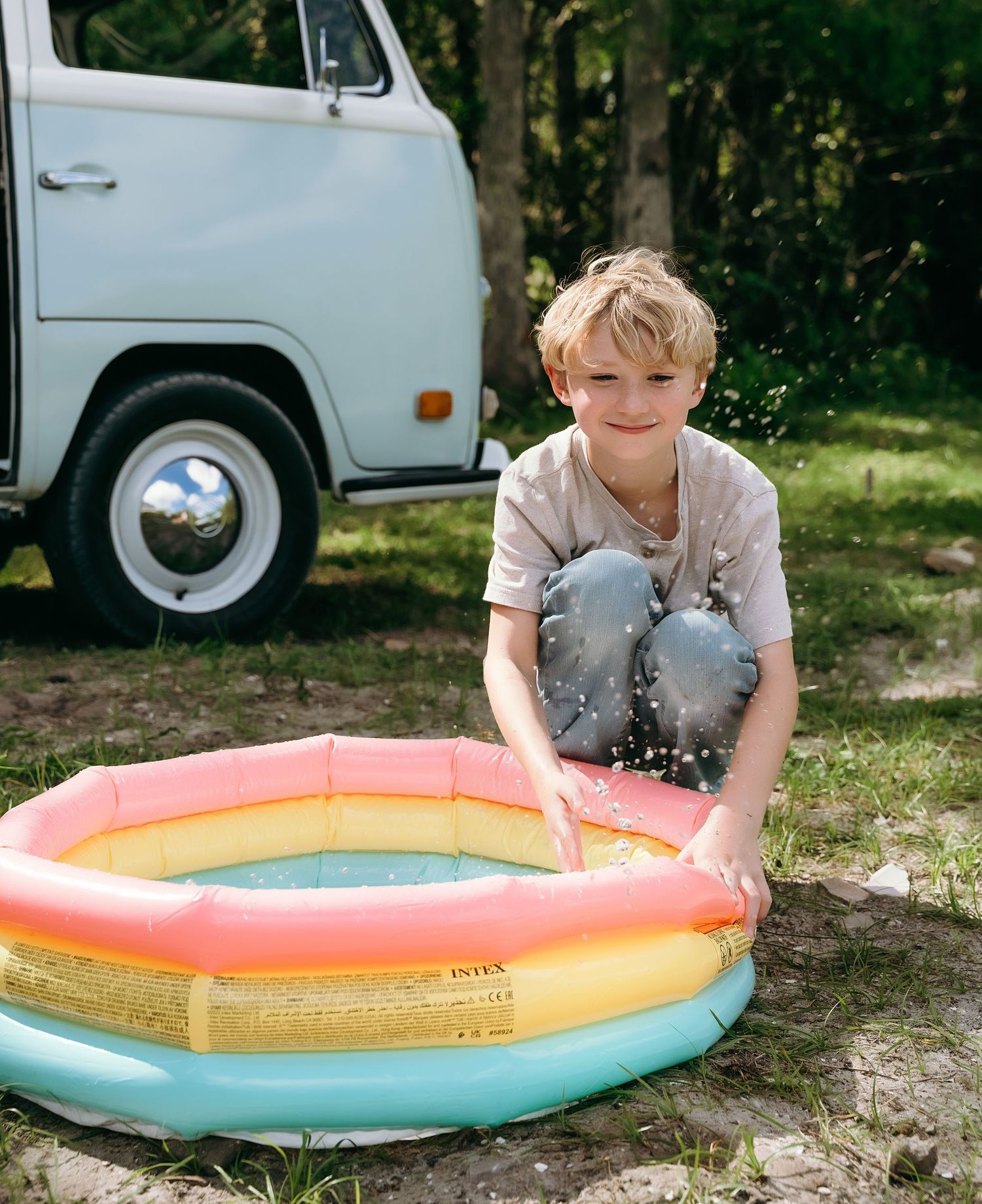 Children playing with a colorful inflatable pool in a backyard setting.