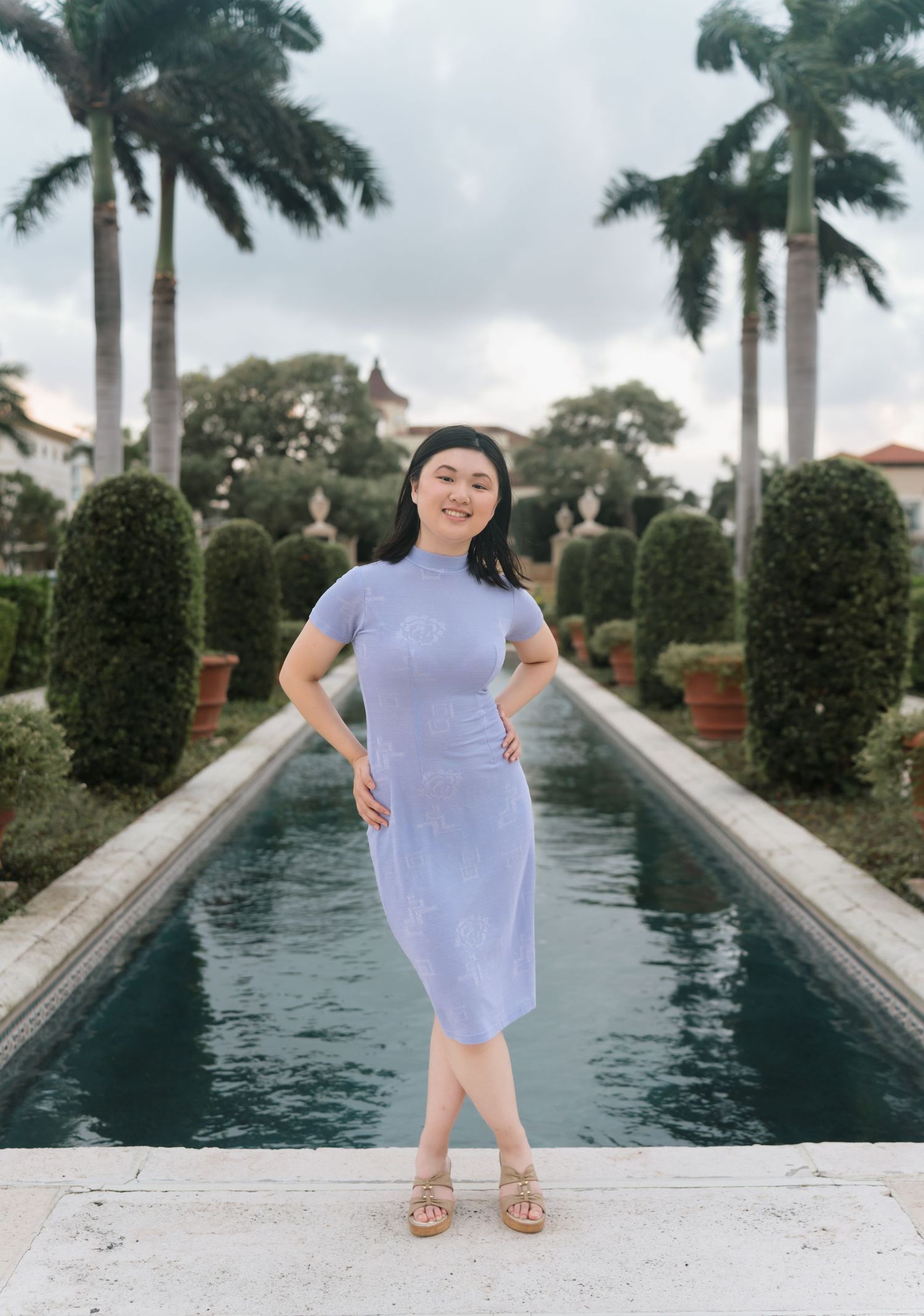 A lavender dress photographed by a reflecting pool with palm trees.