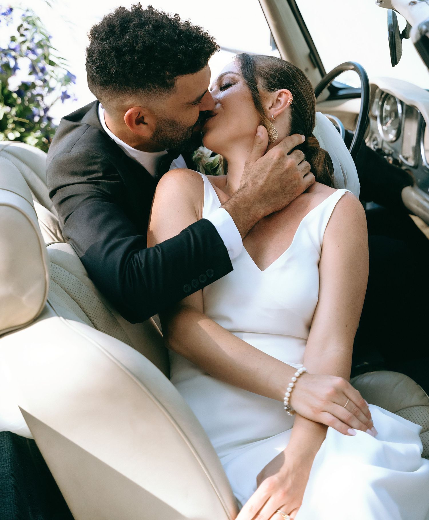 Romantic wedding couple sharing intimate moments in classic car.