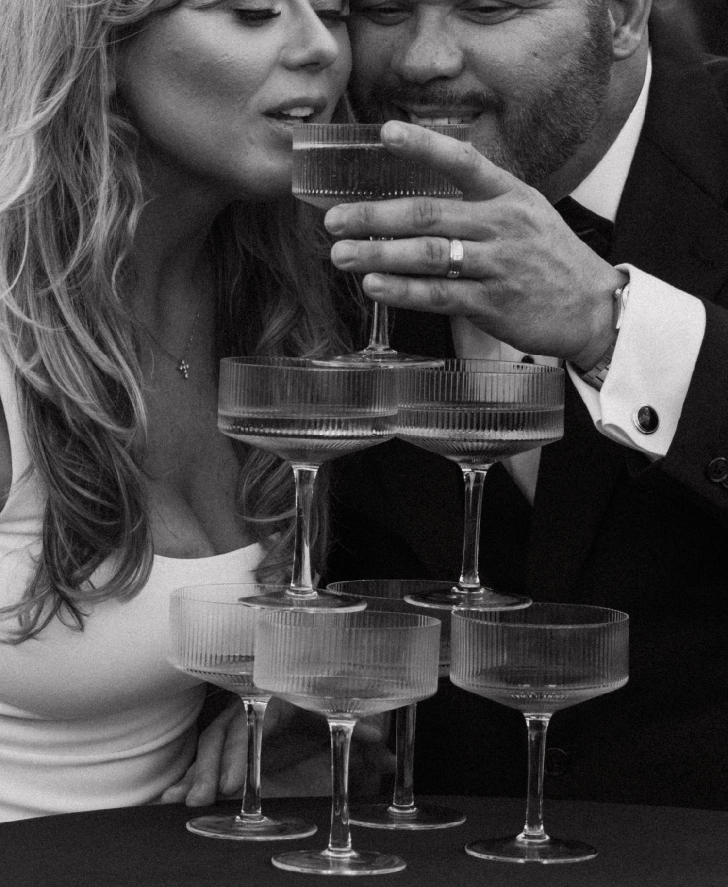 Black and white photo of champagne tower being poured at an elegant event.