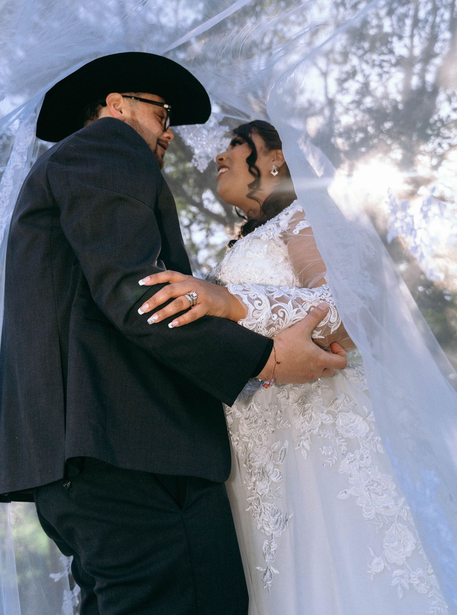 Artistic wedding photos showing close embraces through a delicate lace veil.