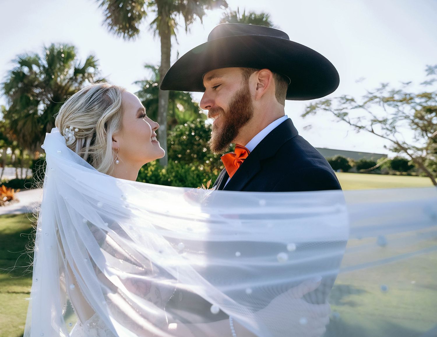 A romantic wedding photoshoot with flowing white veil against a natural outdoor backdrop.