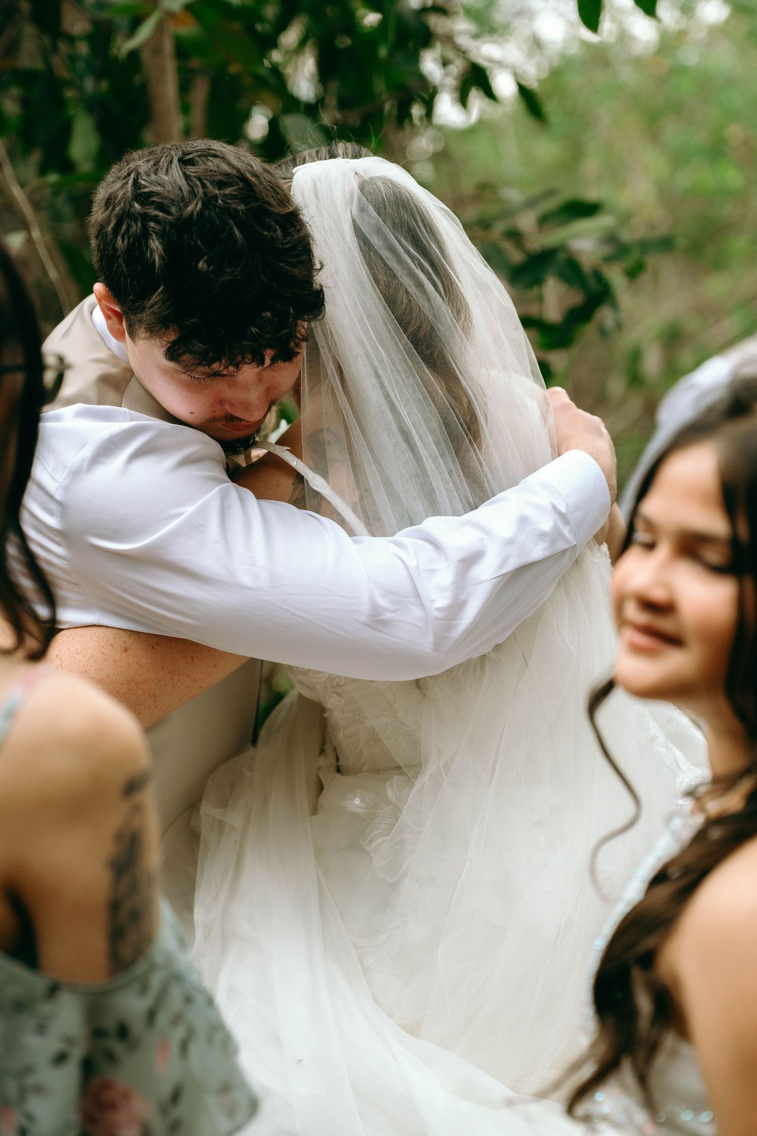 A series of wedding photos showing a couple sharing a romantic kiss under a veil in an outdoor garden setting.