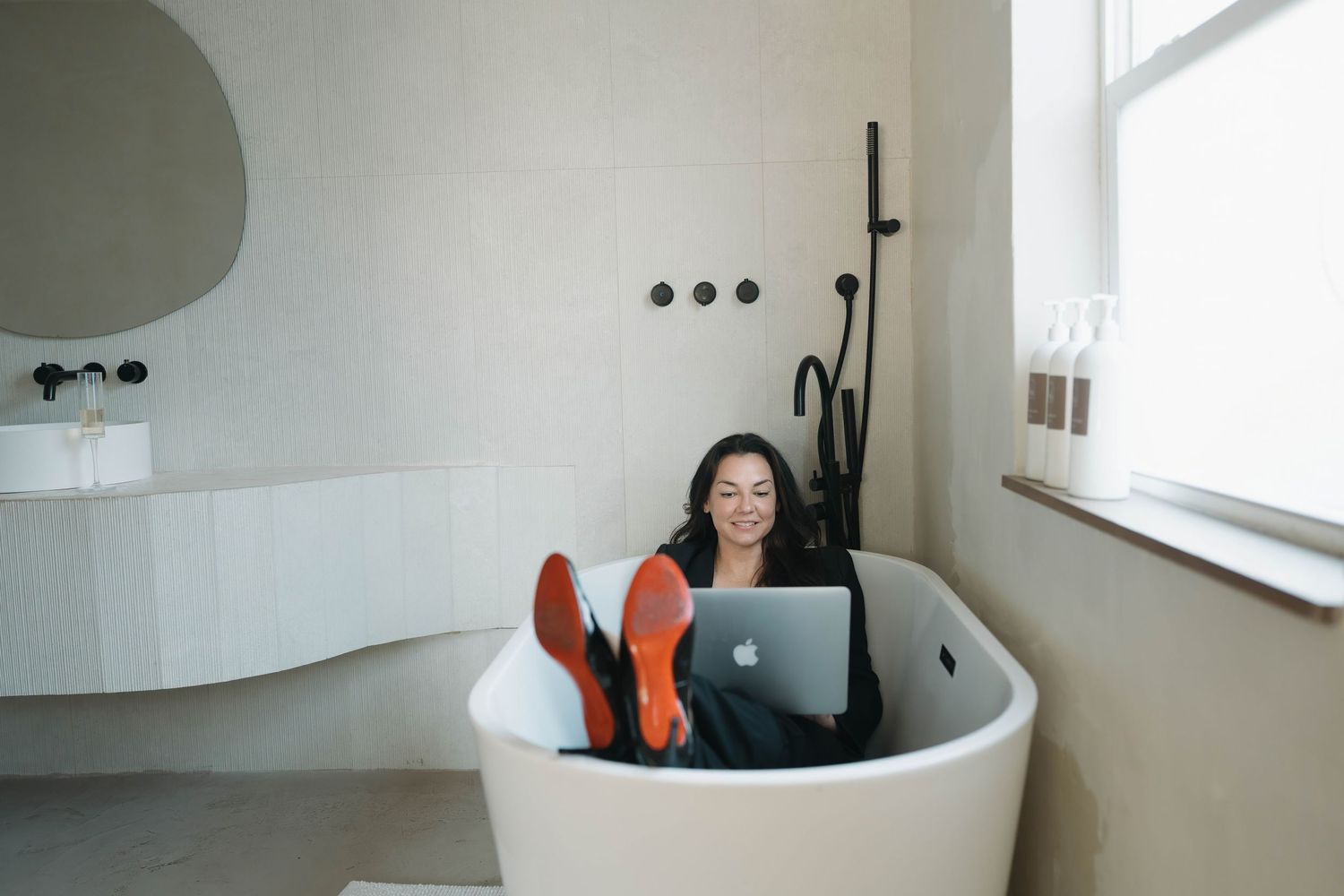 Modern bathroom interior featuring freestanding white tub and matte black shower fixture.