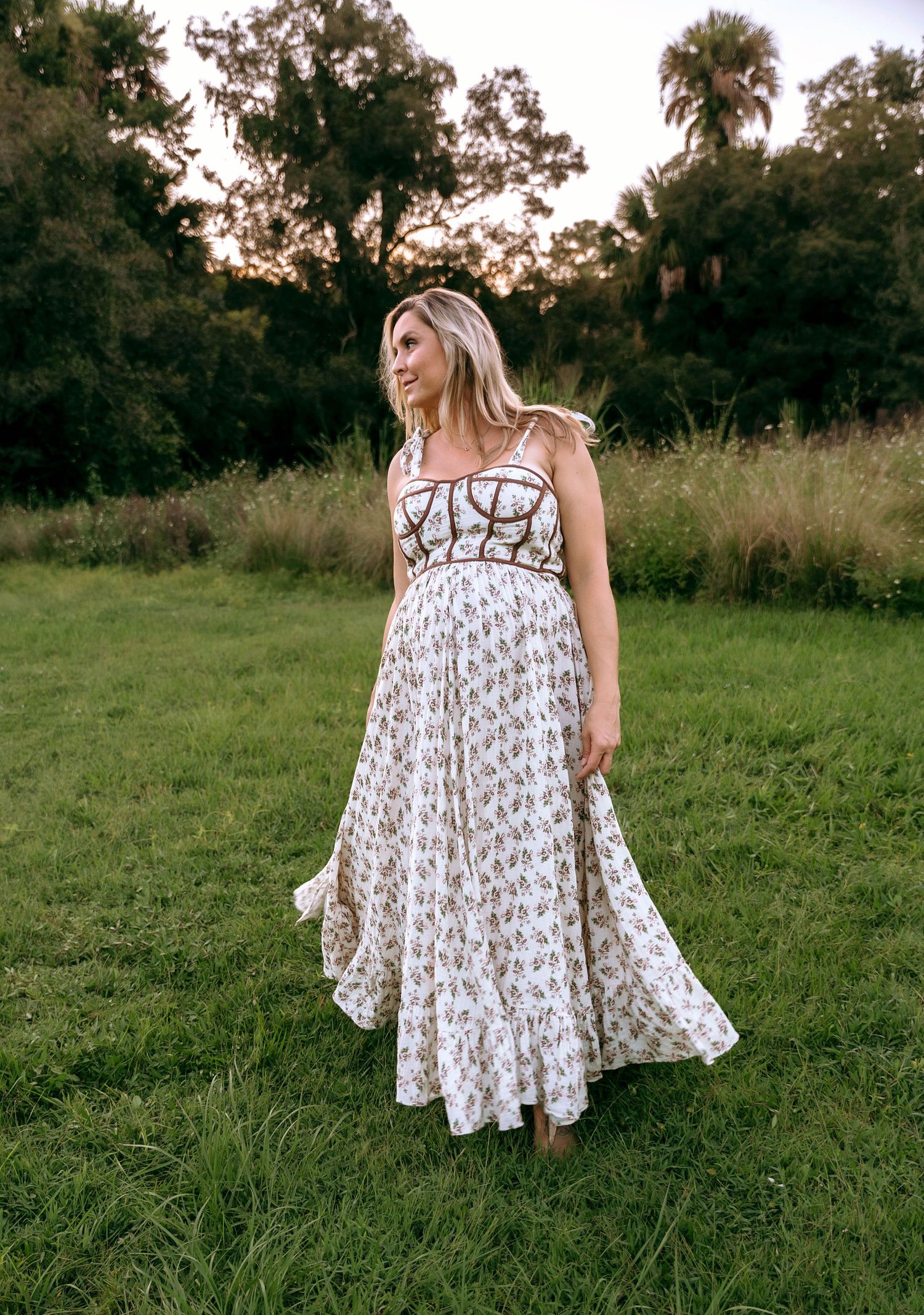 A flowy white patterned dress moves elegantly in a serene meadow setting.