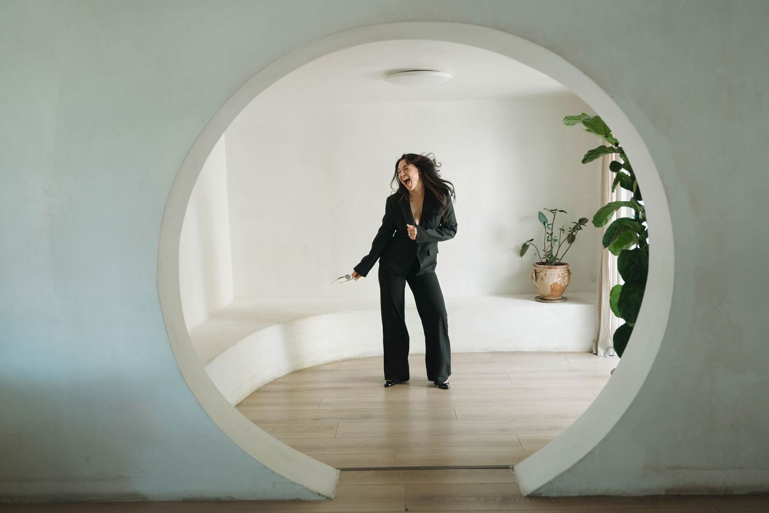 Architectural view through curved doorway showing minimalist white interior space.