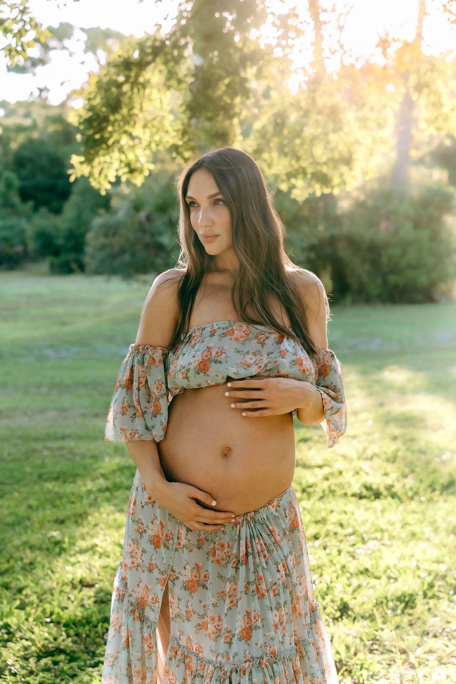 Glowing maternity photos captured in a serene garden setting at sunset.