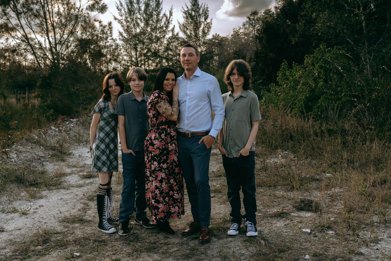 Family of five posing together on a dirt path surrounded by trees at dusk at Colt Farms in Boynton Beach FL..