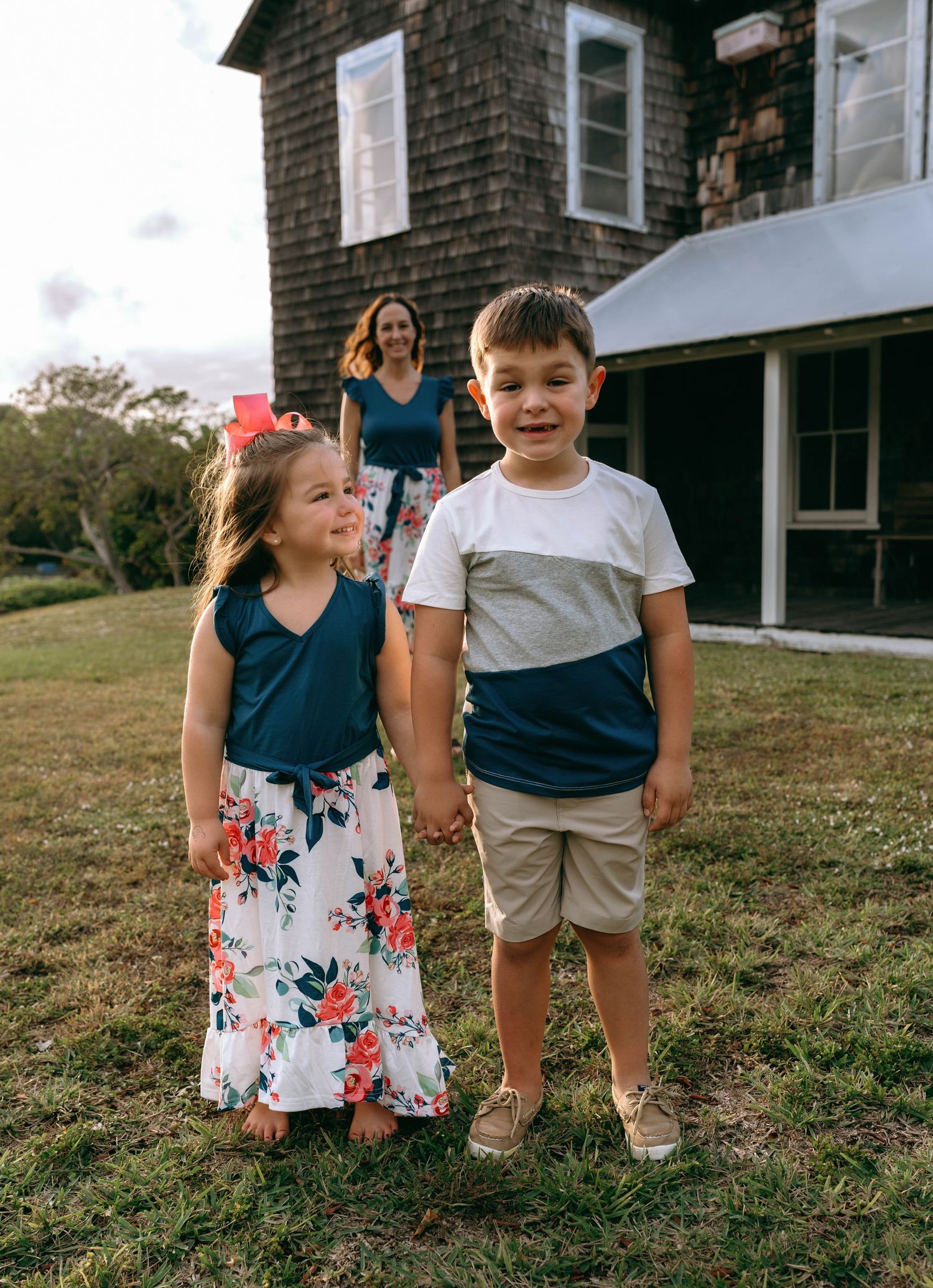 Children playing on the grass in front of a charming rustic house.