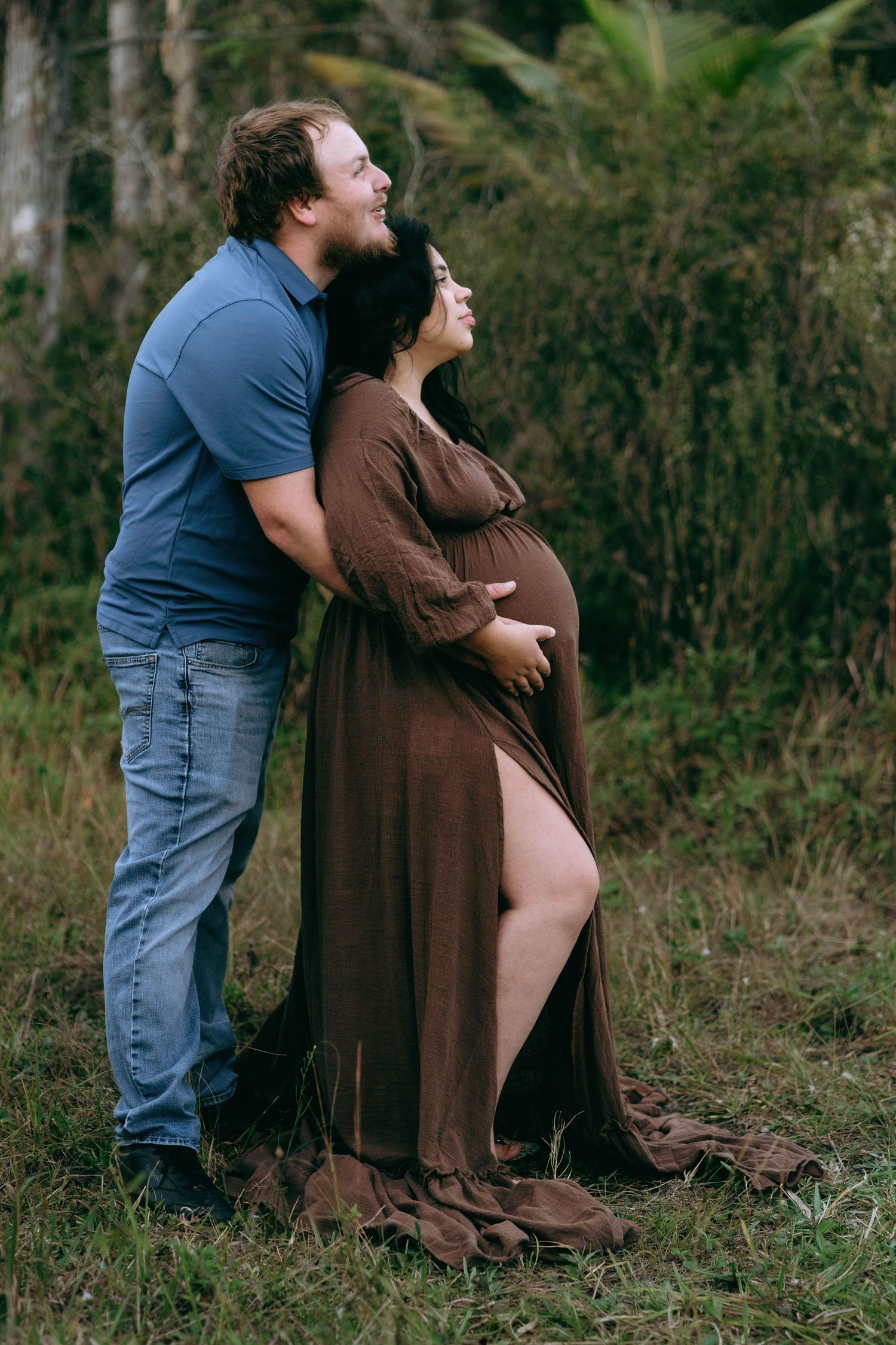 A couple shares an intimate moment outdoors in brown and blue casual attire.