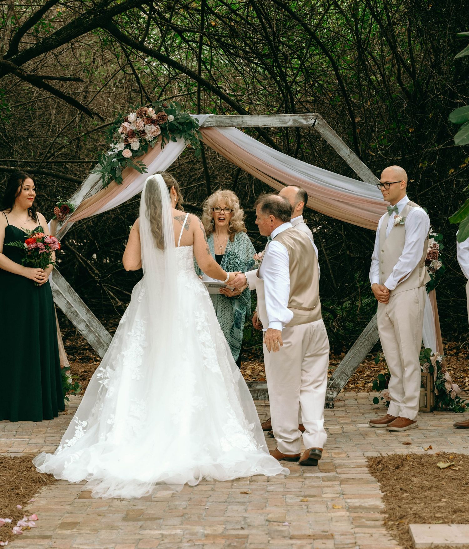 Wedding party dancing and celebrating on outdoor stone patio surrounded by natural greenery.