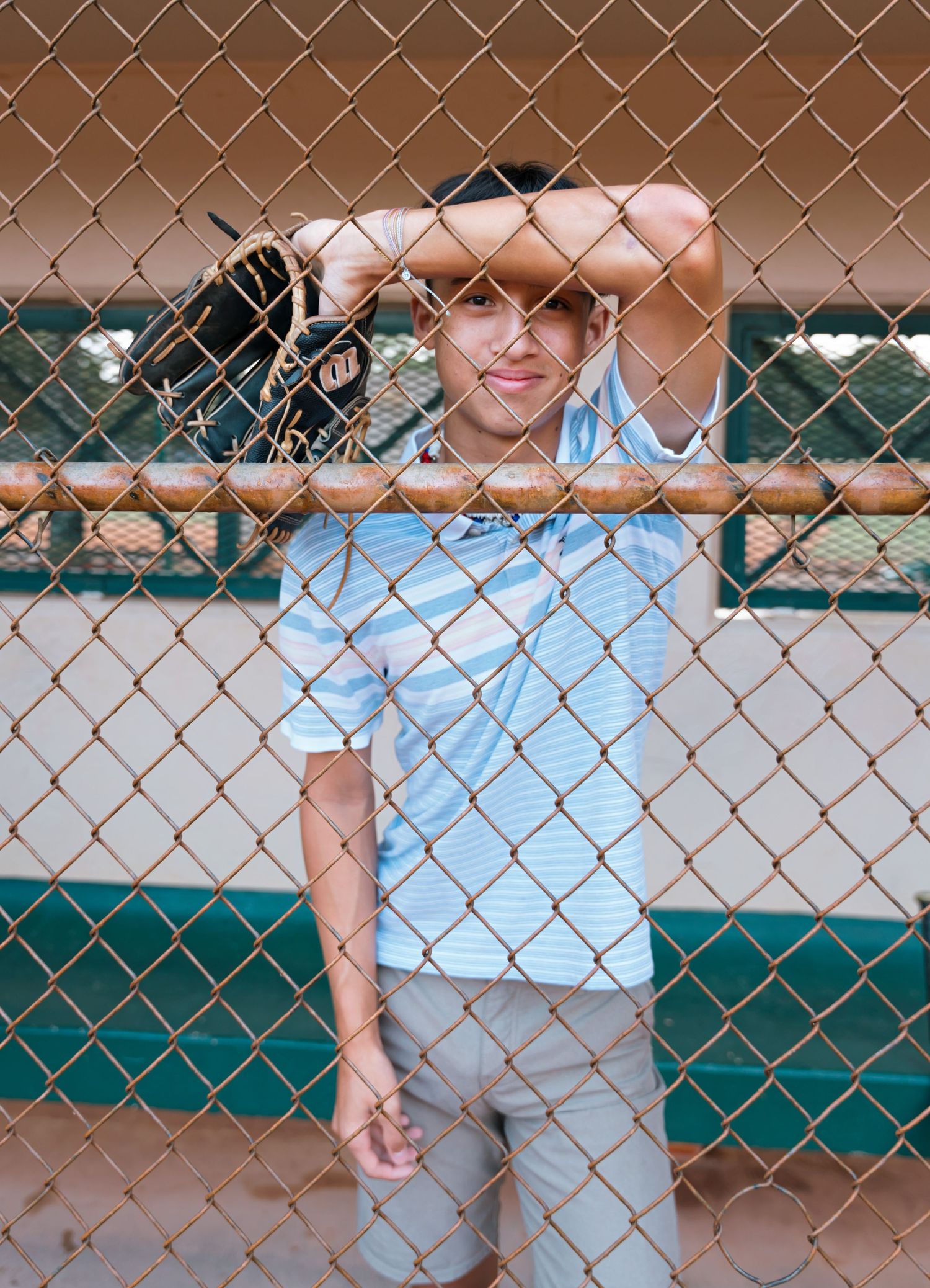 Athletic poses through a chain-link fence at a sports facility.