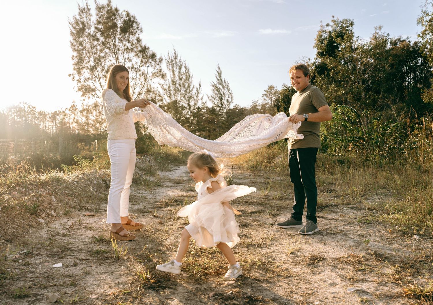 Candid family photoshoot moments captured in warm sunlight on a nature trail.