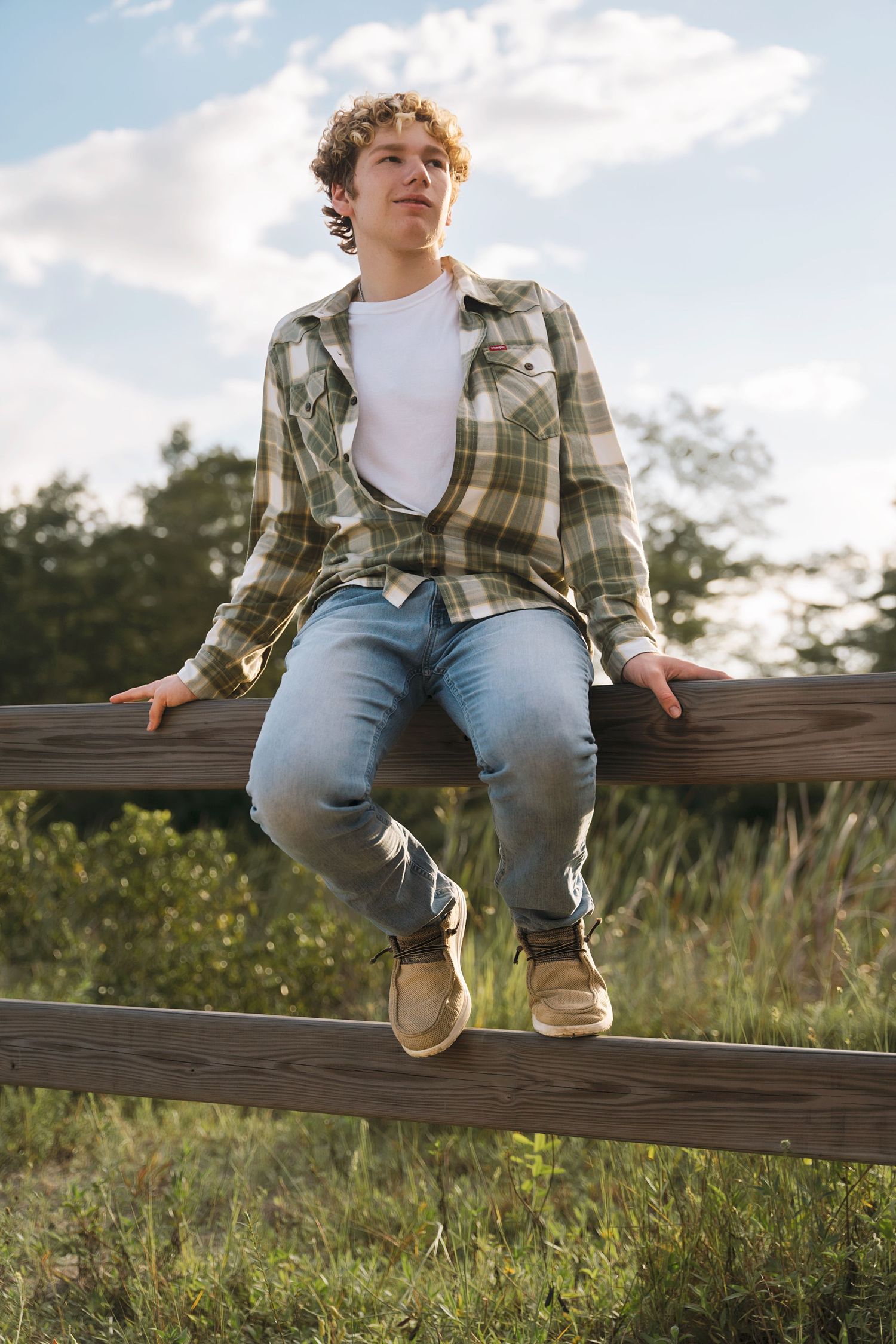 Candid shots sitting on a wooden fence in the countryside at sunset.