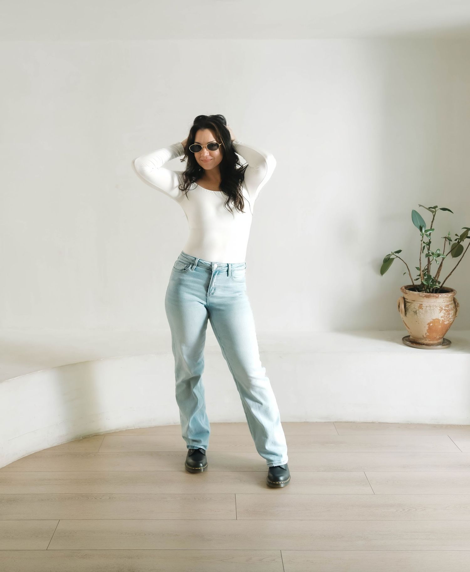 Dancing figure in light denim and white top moves expressively across wooden floor.