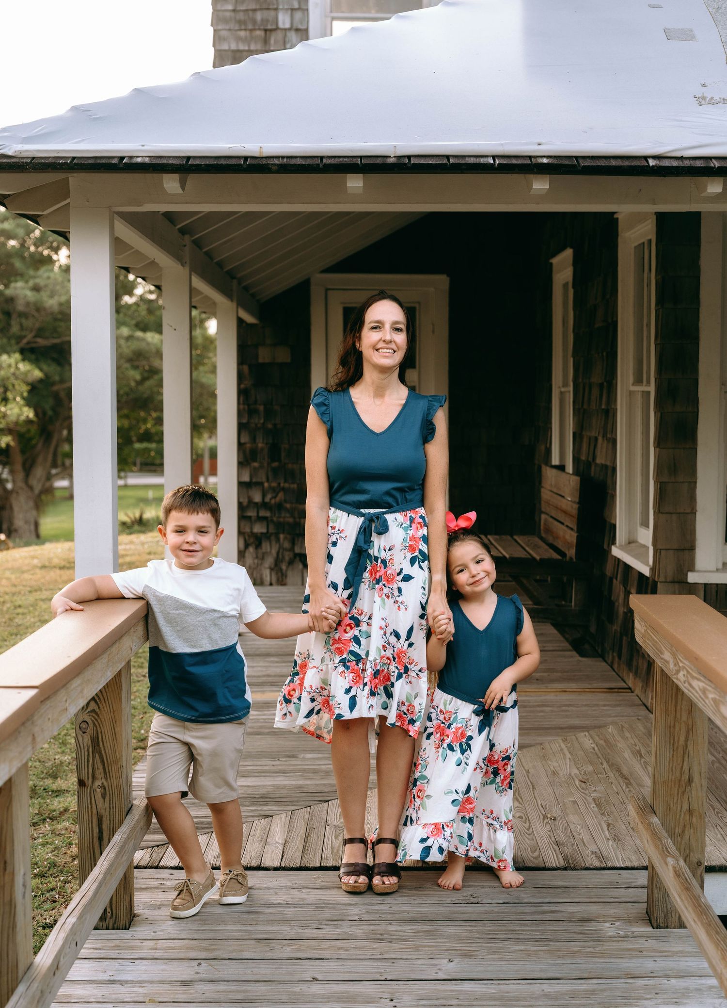 People enjoying time together on a white-columned porch of a shingled house.