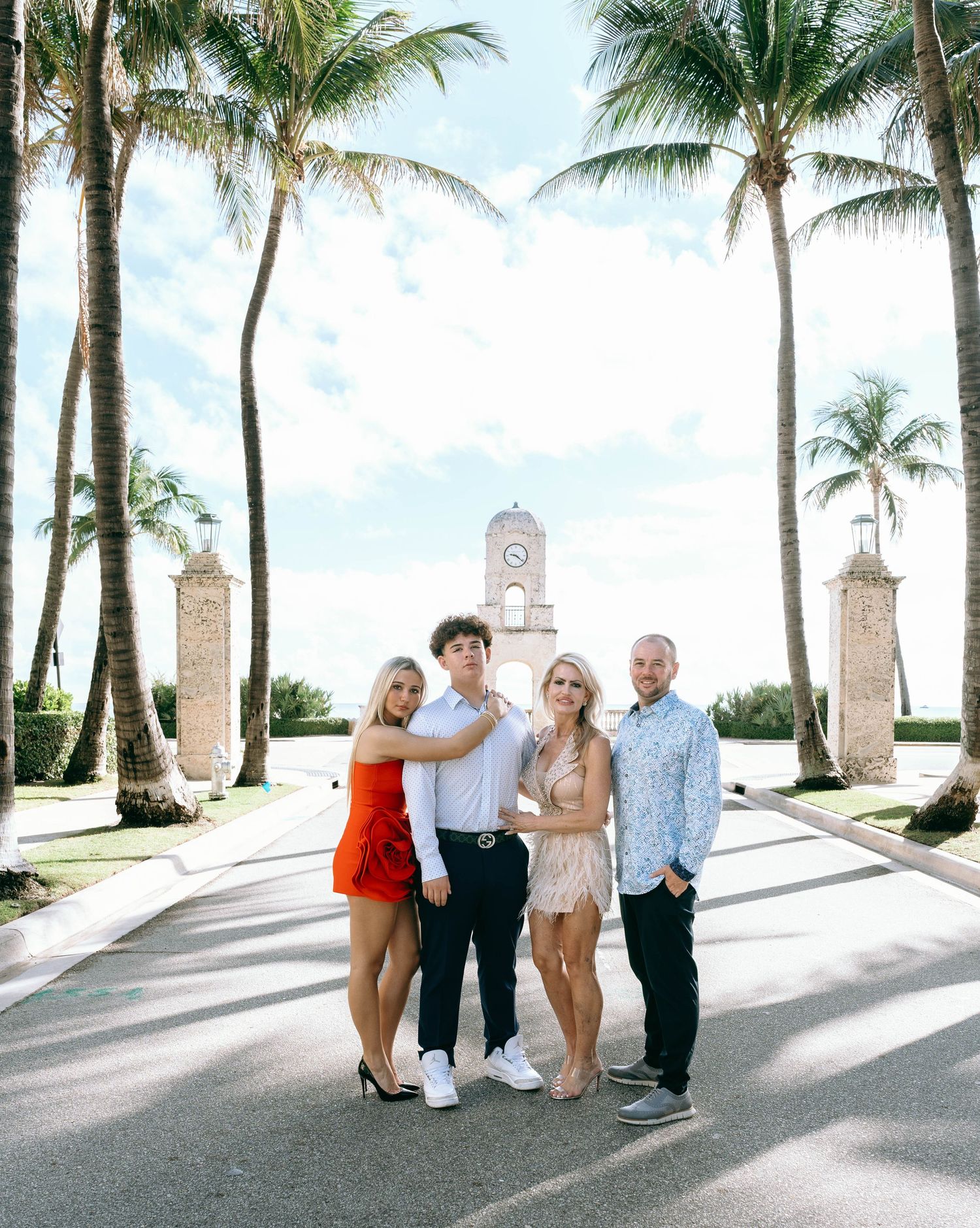 Group photo session along palm-lined pathway with ornate stone pillars.
