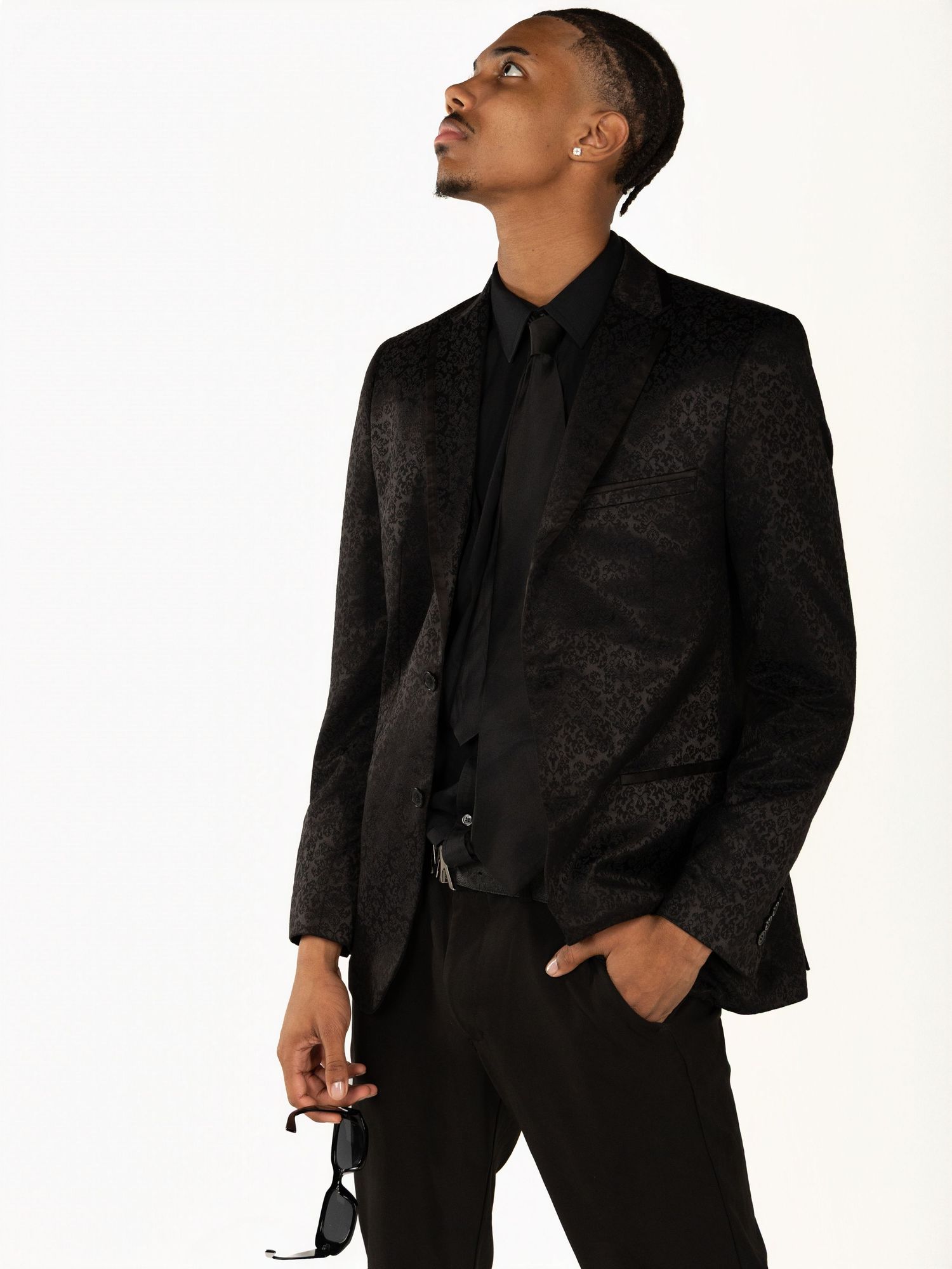 Fashion portrait featuring all-black ensemble with textured blazer in dramatic lighting.