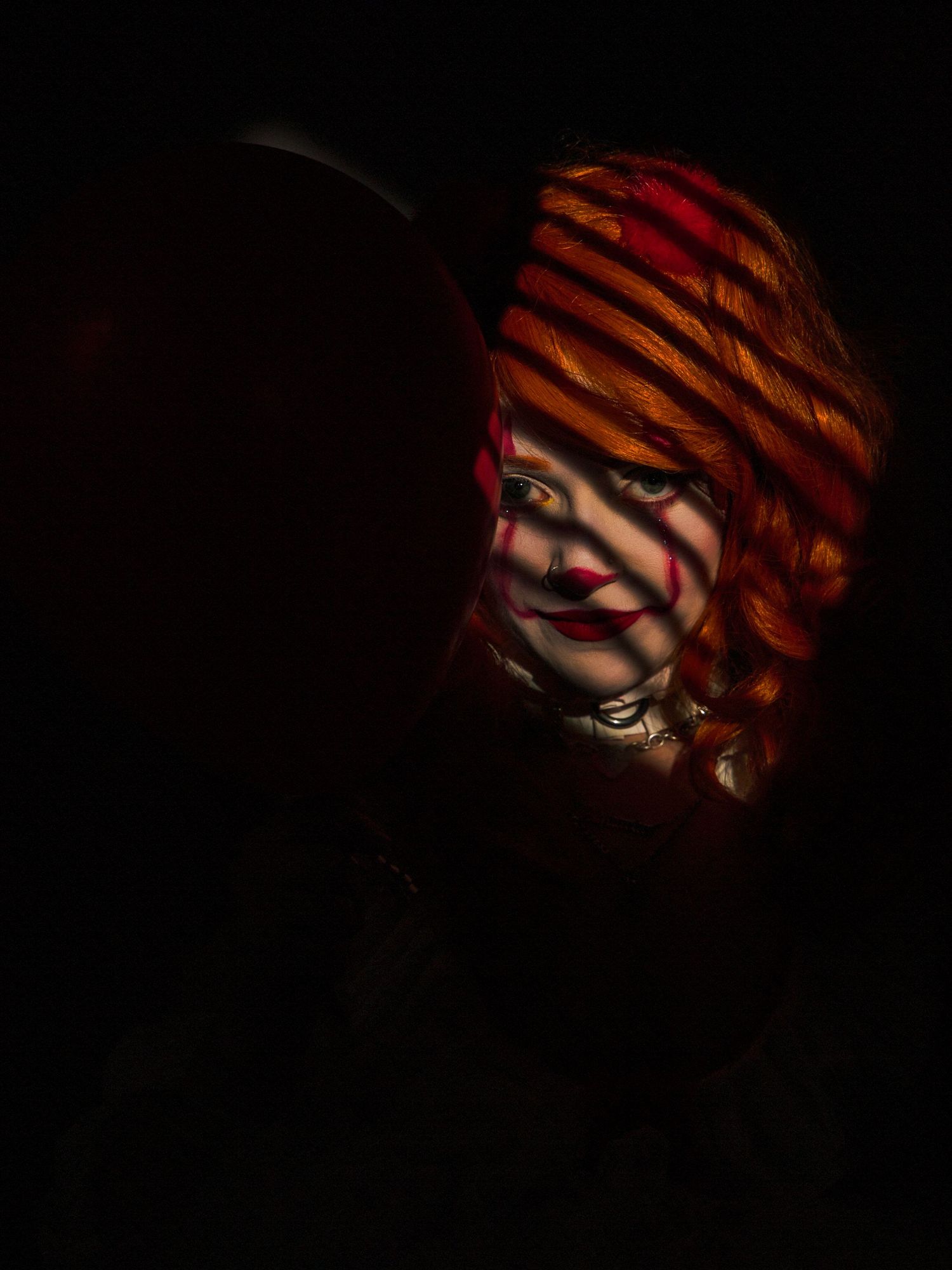 Dramatic low-key portrait with striped lighting effects in dark setting.