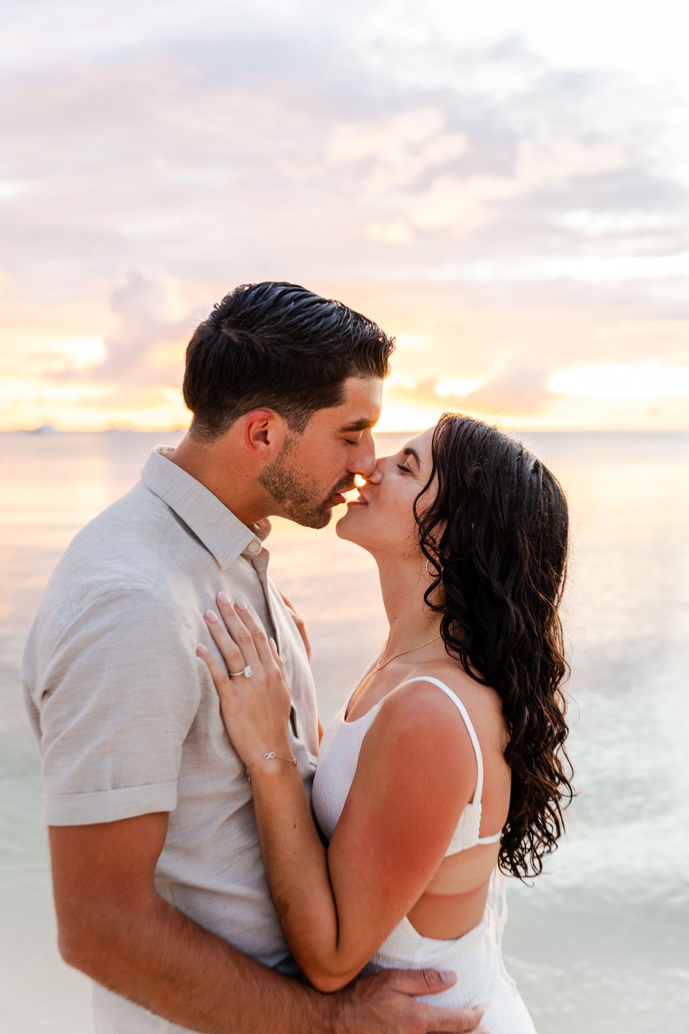 A couple shares a romantic kiss on the beach at sunset in three similar poses.