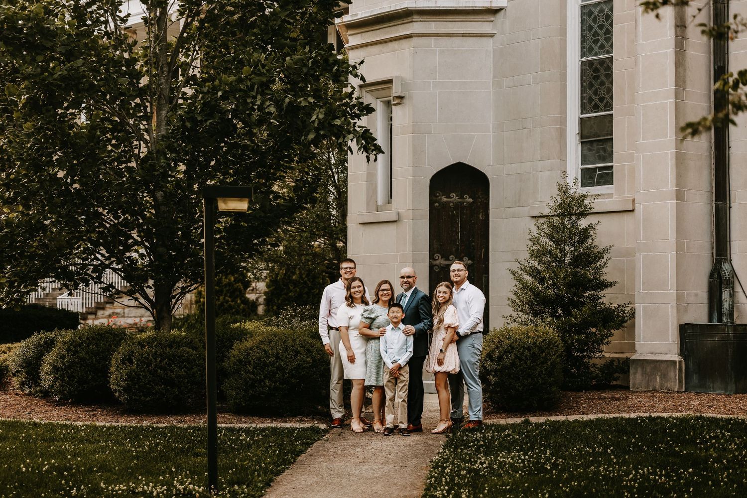 Classic stone building with columns serves as backdrop for family portrait.