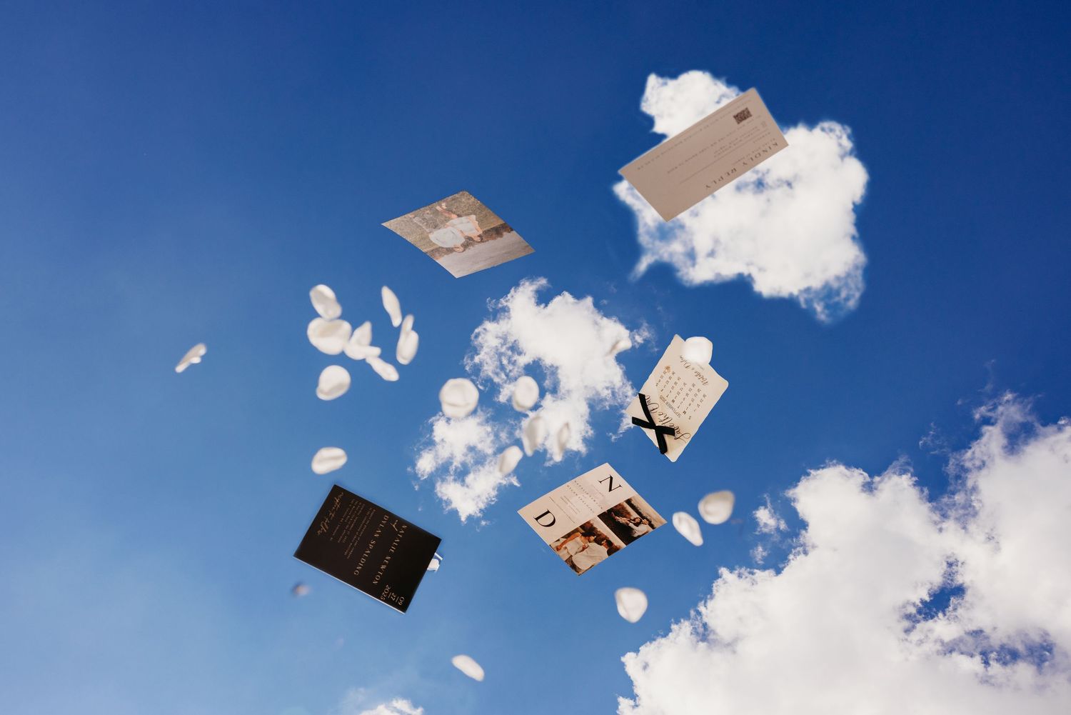 Books and papers flying through a bright blue sky with fluffy white clouds in a dynamic aerial scatter.