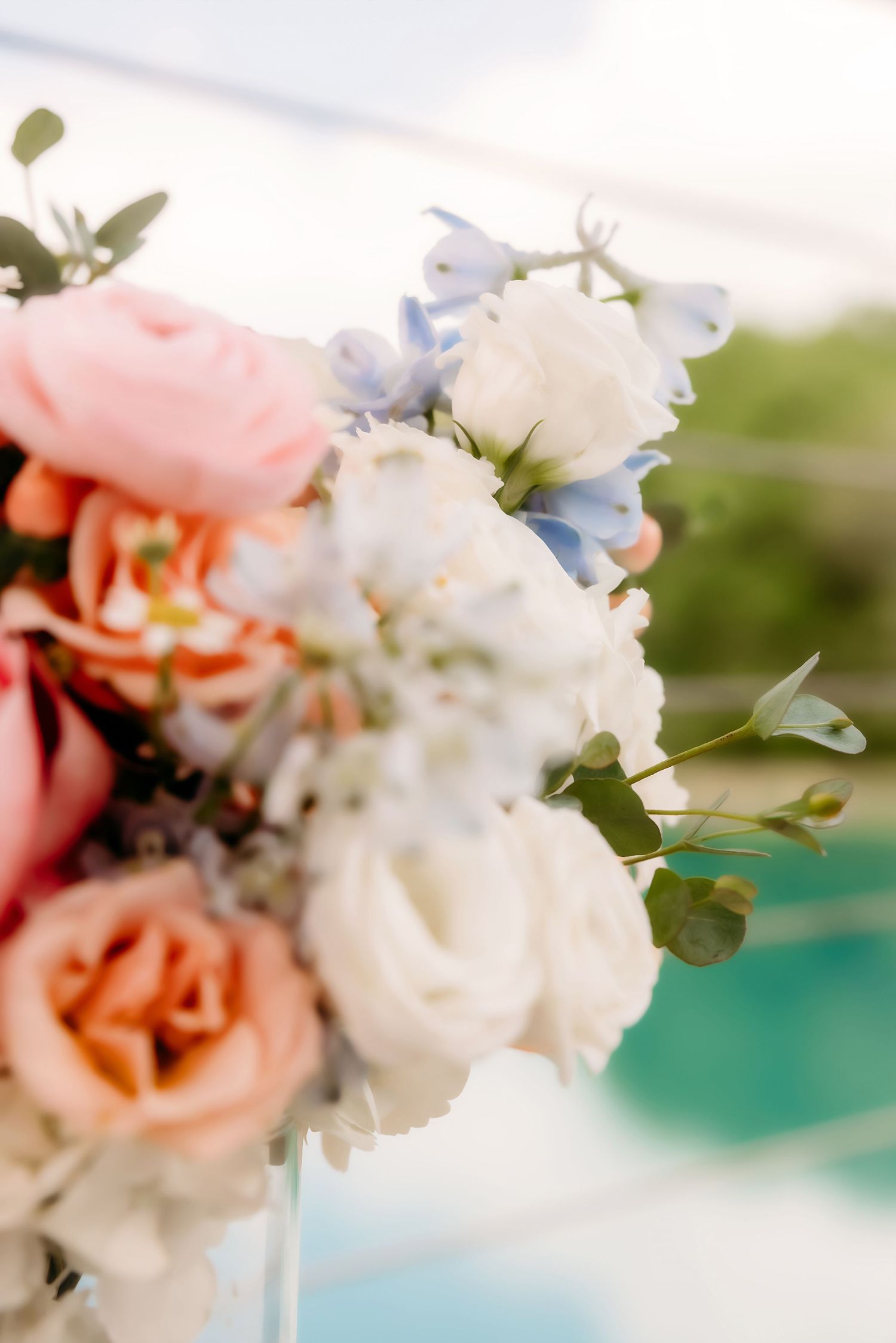 Close-up of elegant wedding floral arrangement featuring white roses, pink peonies, and blue flowers.