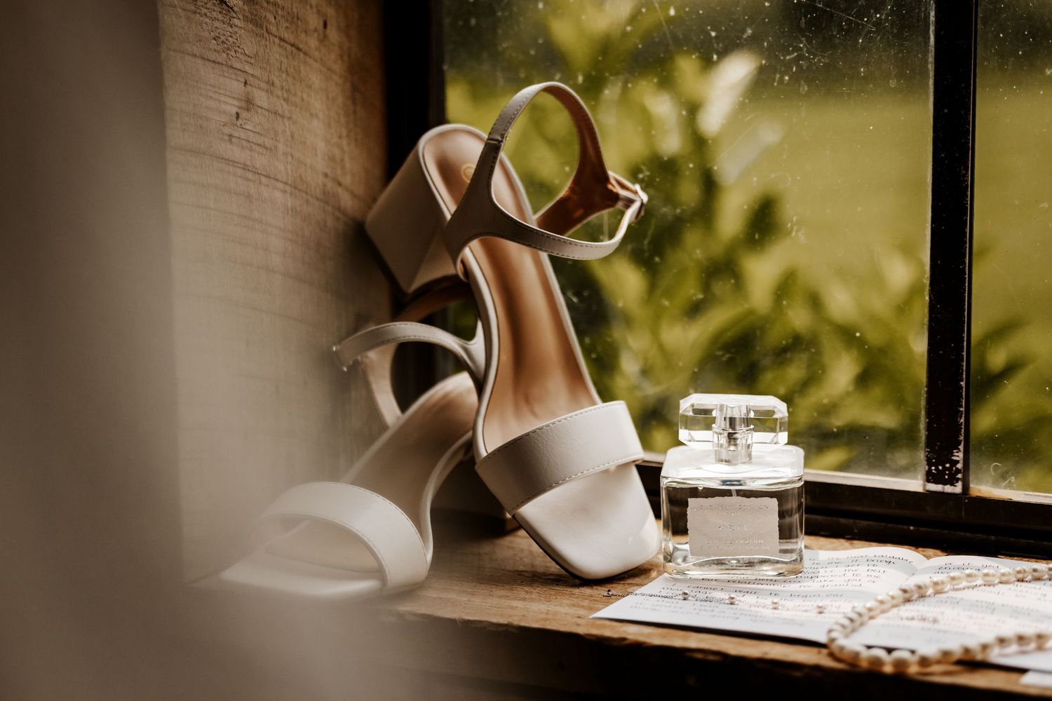 Soft window light illuminating wedding details on a wooden windowsill with delicate shadows at The Venue at Evan's Orchard.