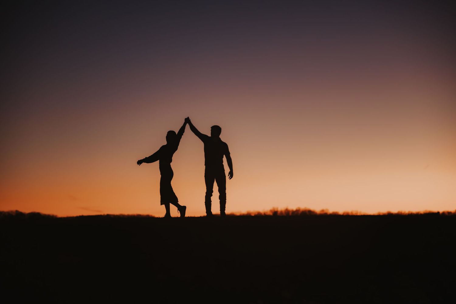 Silhouettes of people standing on a hill against a dramatic Kentucky sunset sky.