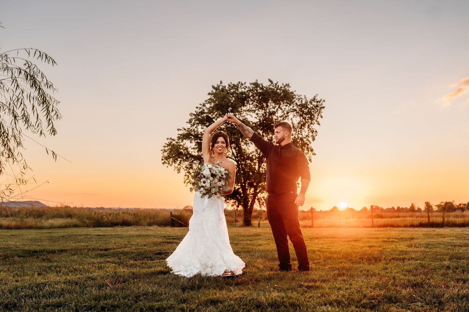 A golden sunset wedding portrait in an open field with trees silhouetted against the sky at The Marion Barn Wedding Venue.